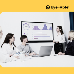 A woman stands in front of a television and gives a presentation to four people sitting at a desk