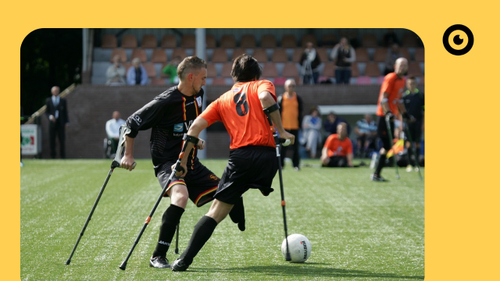 Eine Person an Krücken spielt Fußball.