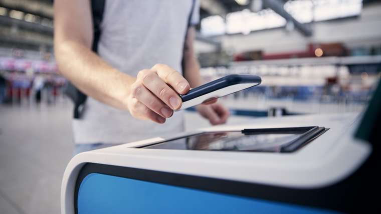 Traveler using smartphone for mobile check-in at airport terminal