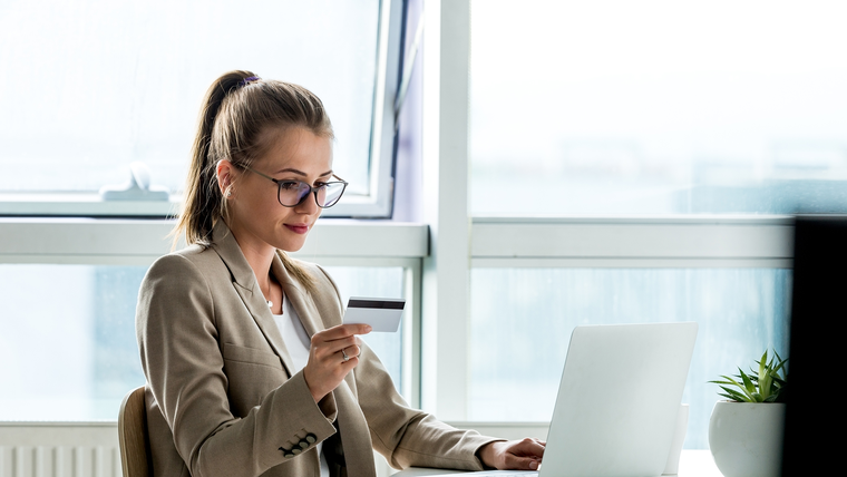 Woman holding a credit card and using a laptop.