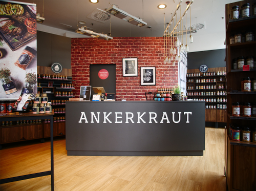 Interior view of an Ankerkraut spice store featuring a counter, red brick walls, and shelves filled with spice jars.