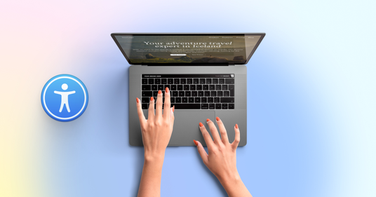 Bovenaanzicht van een laptop waarop een website wordt getoond, met twee handen die op het toetsenbord typen. Links naast de laptop staat een blauw toegankelijkheidspictogram met een persoon-icoon.