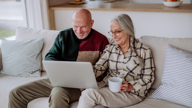 Coppia di anziani sorridenti che usano un computer