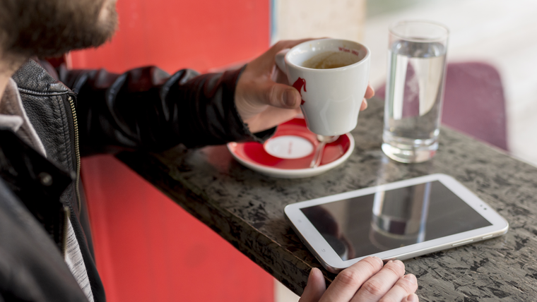 Close-up of a tablet and coffee on a table in a café.