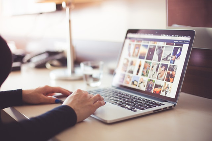 Eine Person scrollt auf einem Laptop durch Bilder.