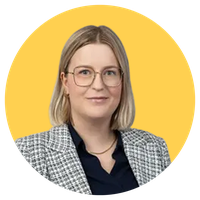 Professional headshot of a smiling woman with blonde bob and glasses, wearing a checked blazer and dark blouse on a yellow background.