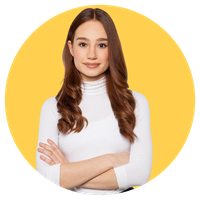 Woman with long brown hair wearing a white turtleneck, arms crossed, smiling confidently against a yellow circular background.