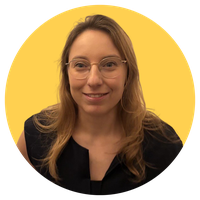 Woman with long hair and glasses, wearing a black top, smiles against a yellow background.