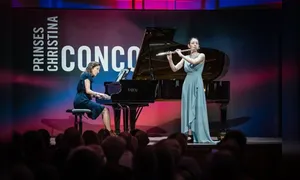 Two musicians perform on stage; a pianist on the left and a flutist on the right, in front of a sign reading "Prinses Christina Concours."