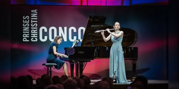 Two musicians perform on stage; a pianist on the left and a flutist on the right, in front of a sign reading "Prinses Christina Concours."