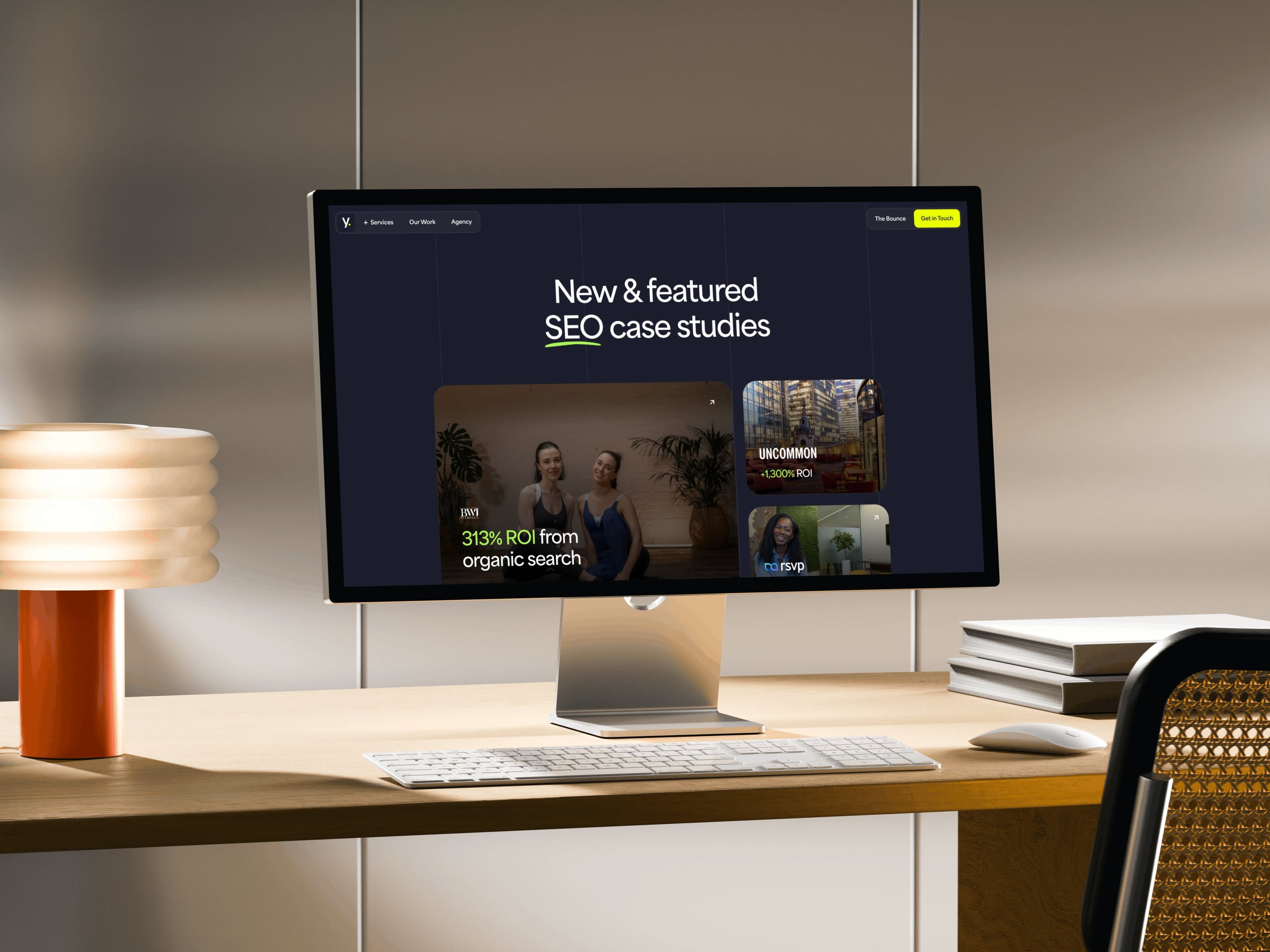 Computer monitor on desk displaying a webpage titled "New & featured SEO case studies" with case study thumbnails.