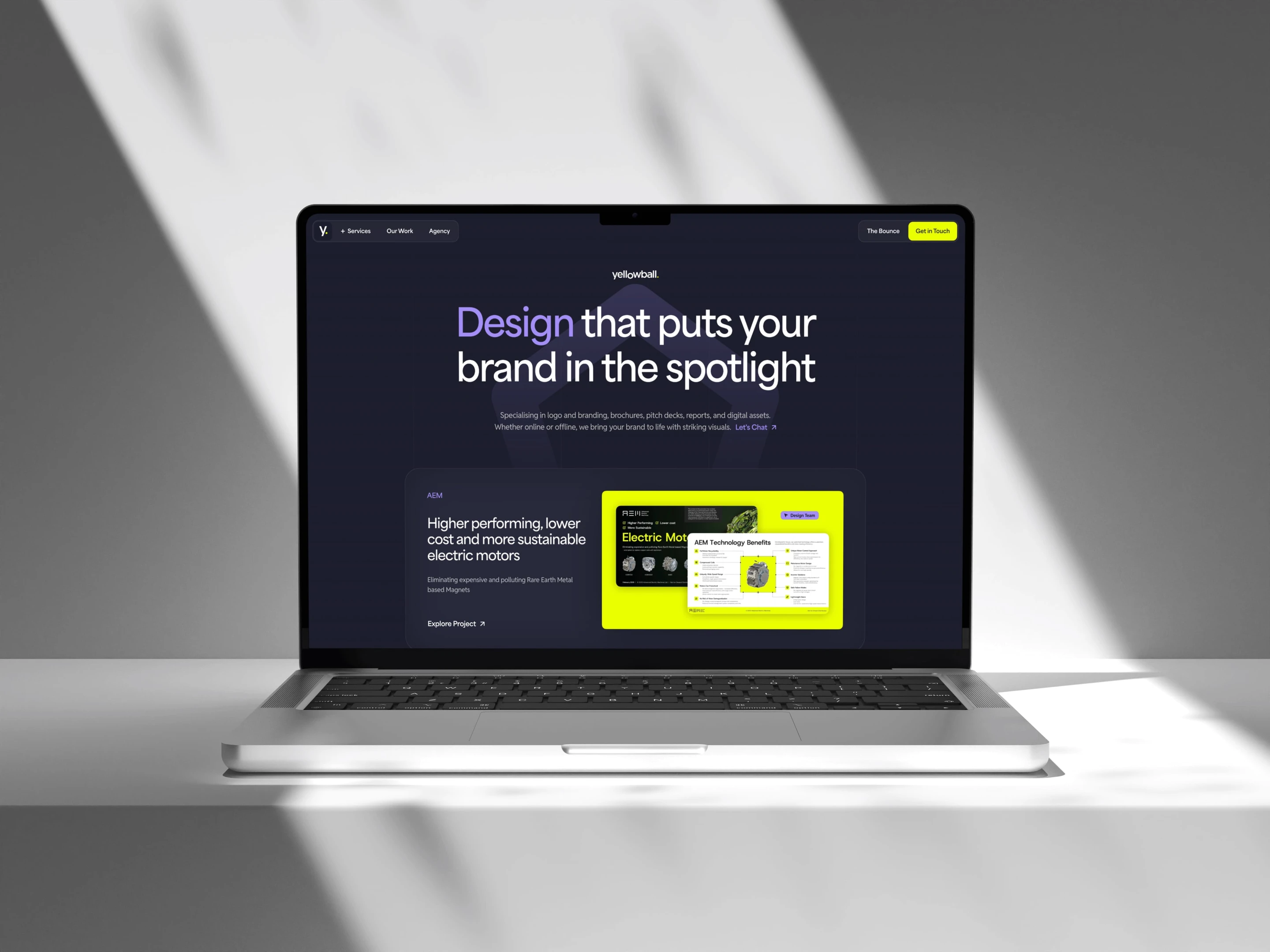 Laptop on a white surface displaying a website with the headline "Design that puts your brand in the spotlight" on a dark background.