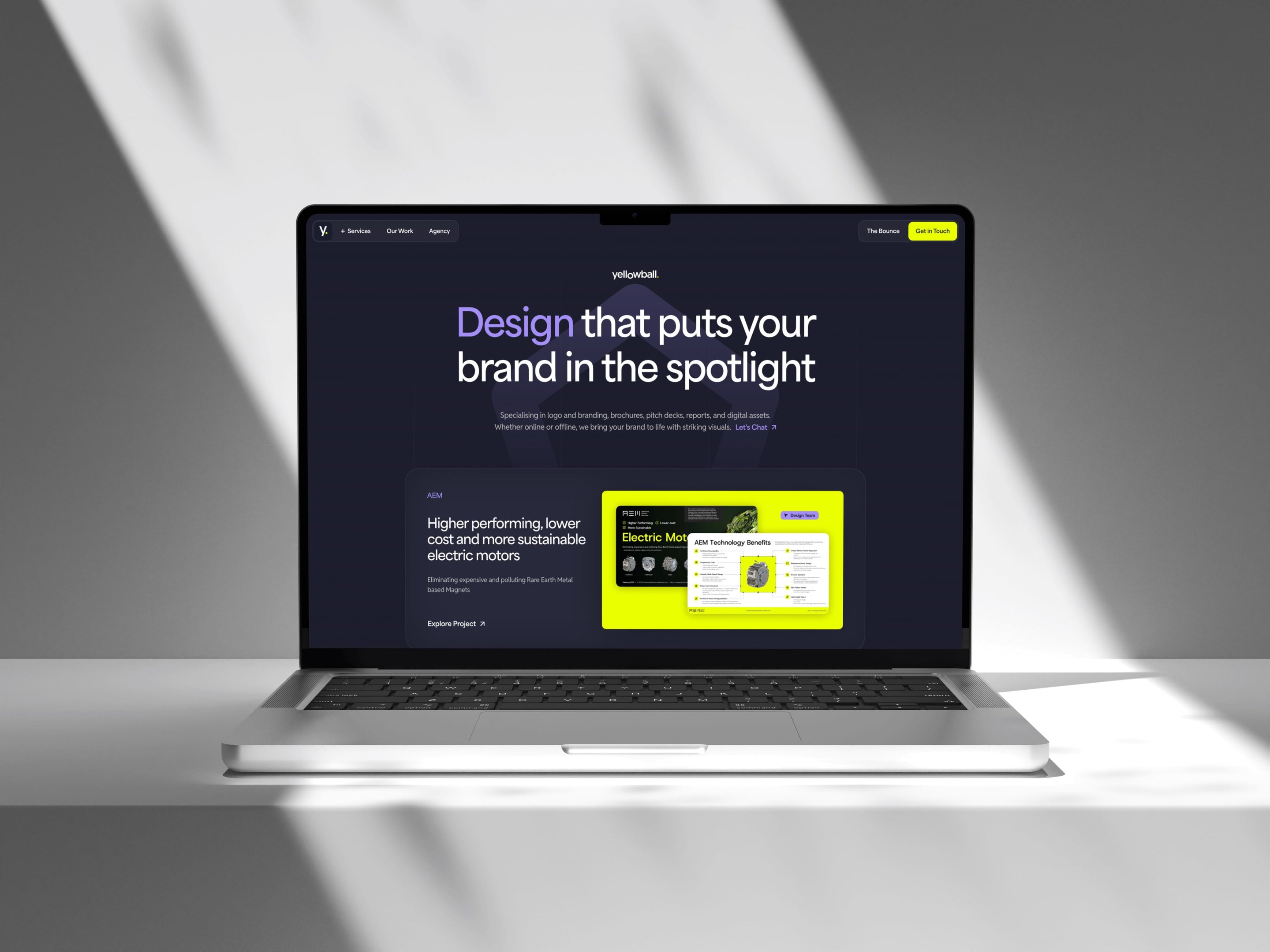 Laptop on a white surface displaying a website with the headline "Design that puts your brand in the spotlight" on a dark background.
