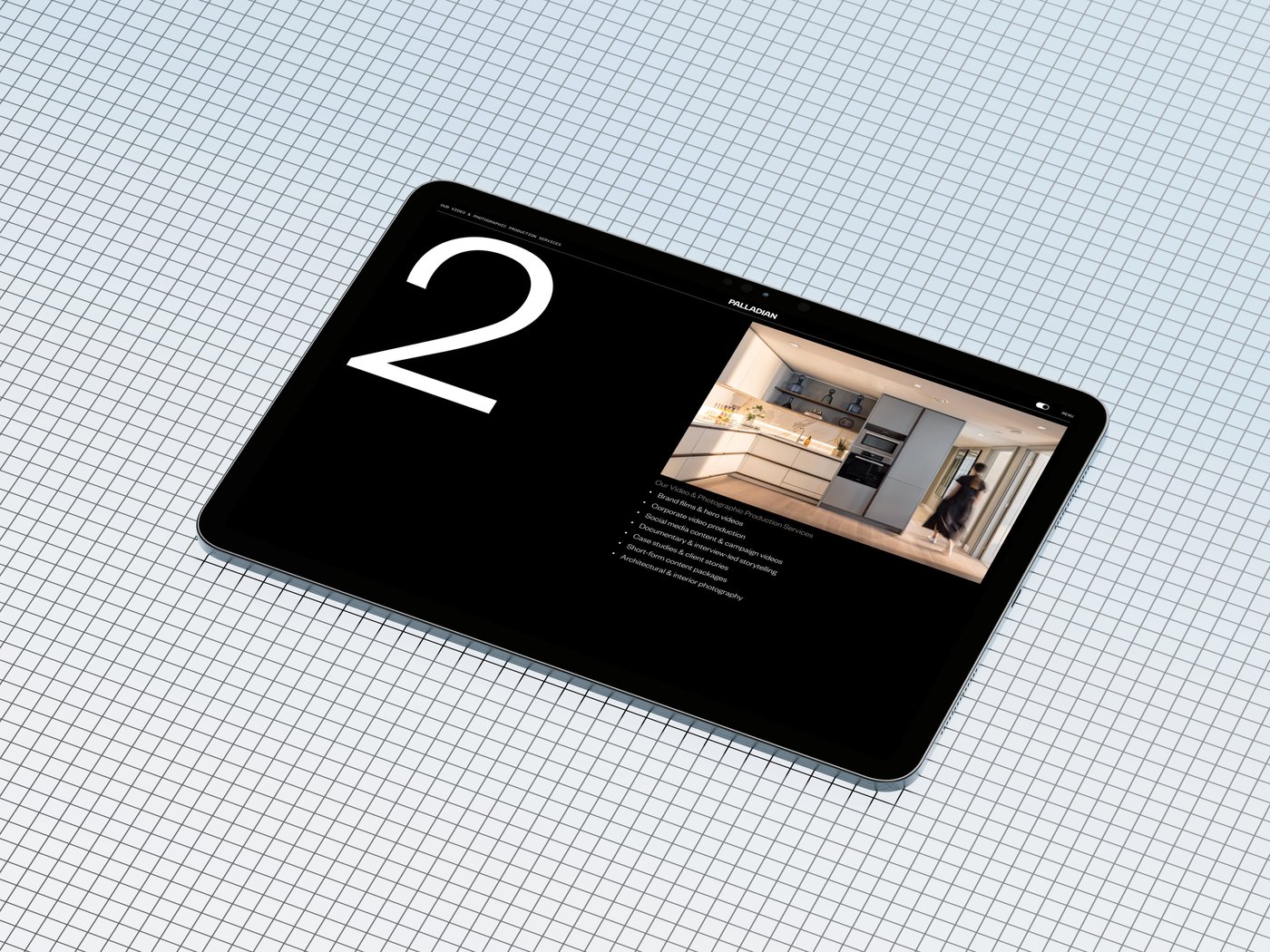 A tablet displaying a kitchen interior design on a grid-patterned surface, with a large number "2" and text on a black background.