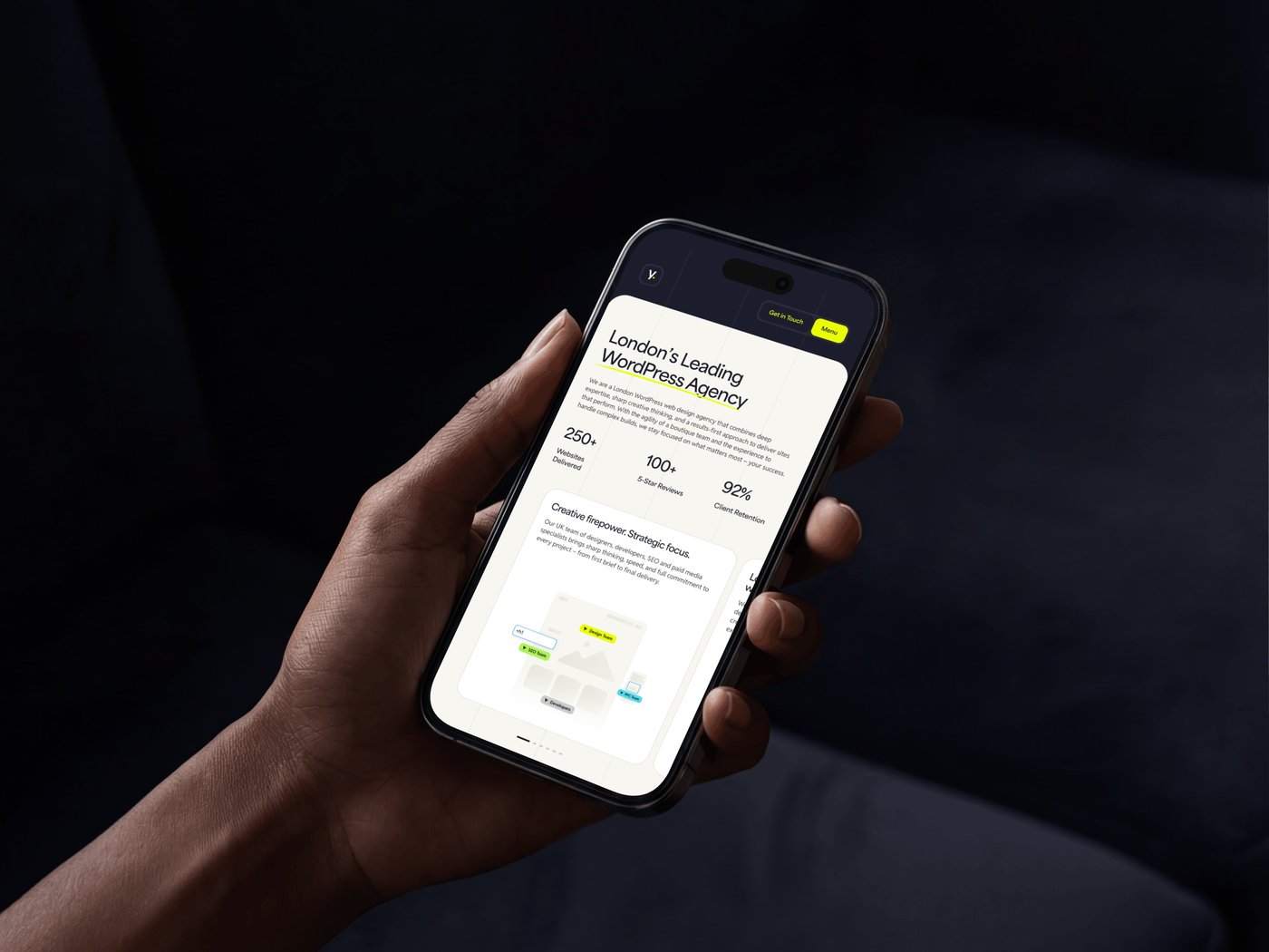 Hand holding a smartphone displaying a webpage titled "London's Leading WordPress Agency" with statistics and text.