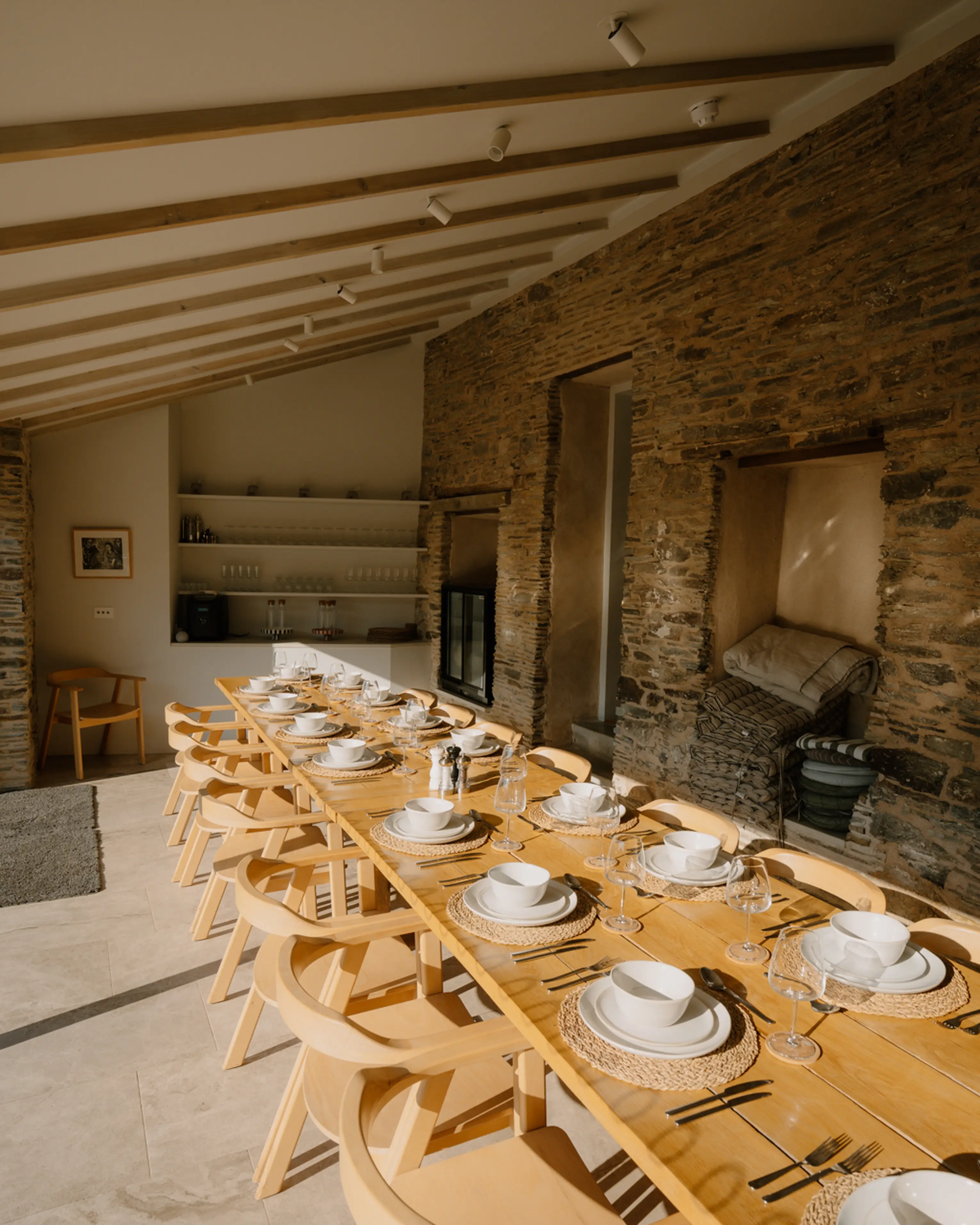 Group dining table set against the exposed stone wall and beams of the converted stables at ARC Padstow