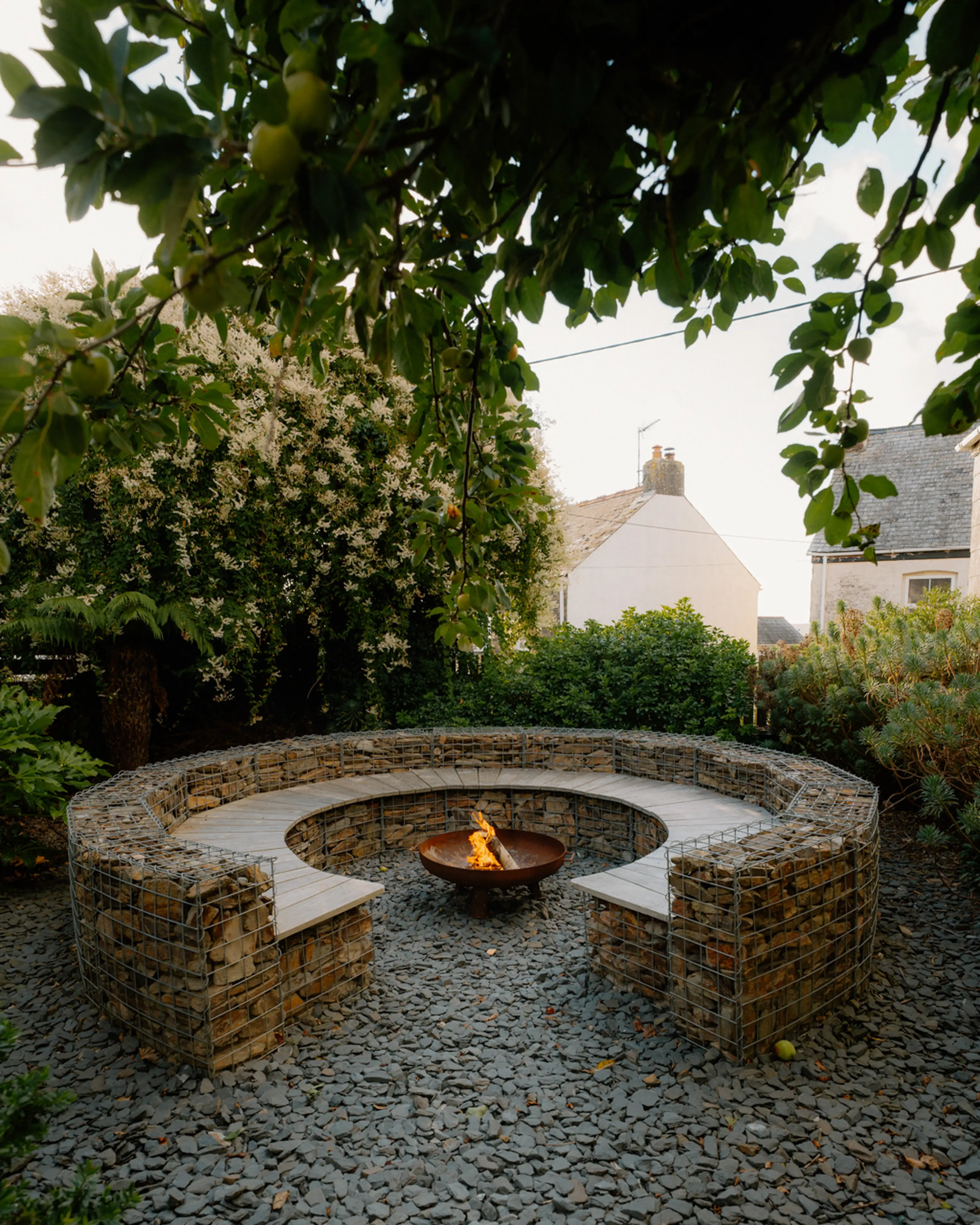 Circular stone firepit in the planted garden at ARC Padstow on a summer evening