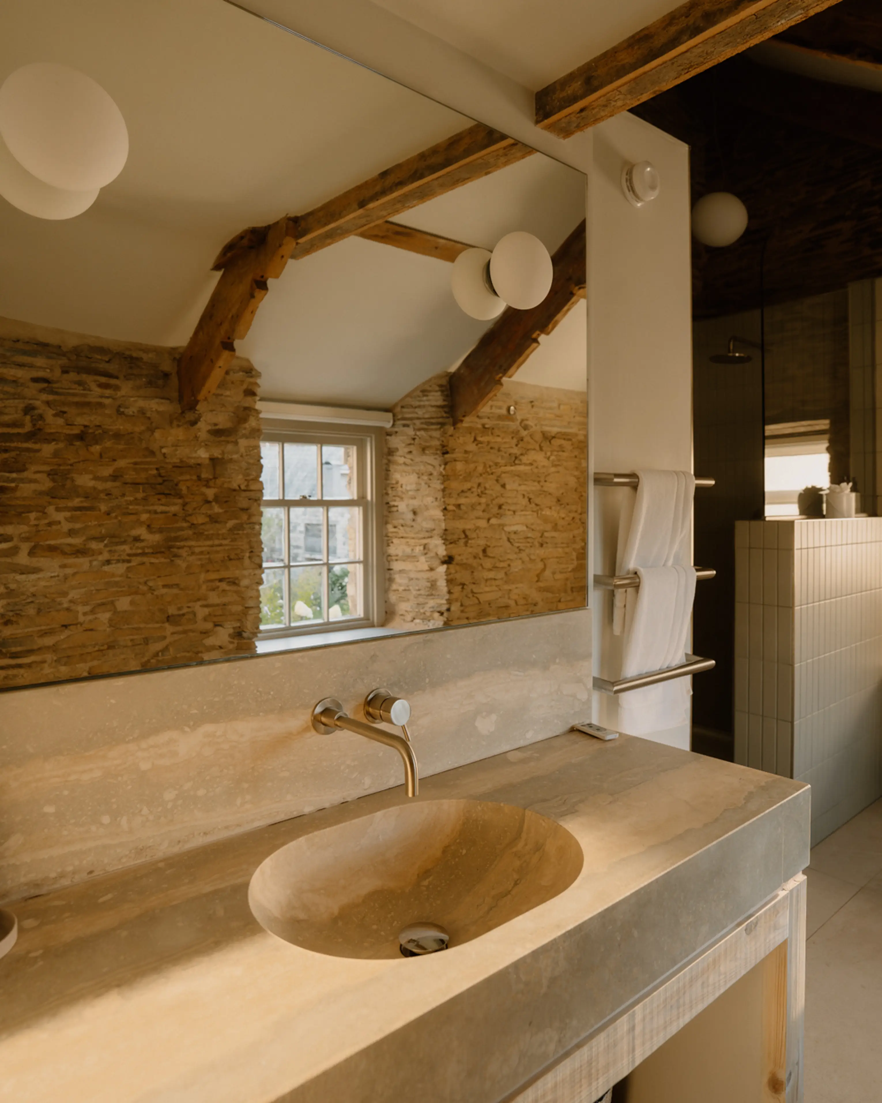 Stone basin set beneath a beamed window in a bathroom at ARC Padstow