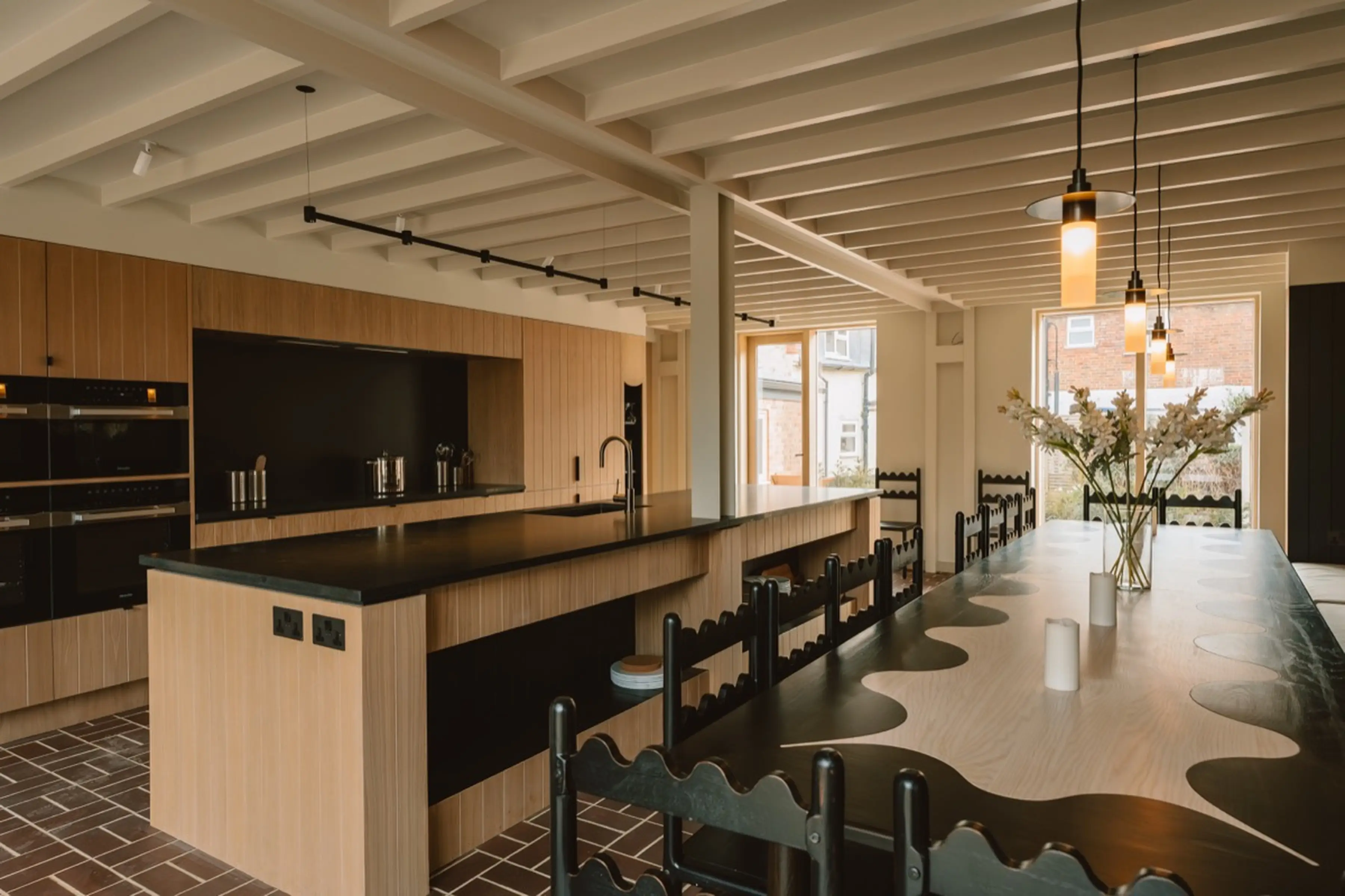 Kitchen and dining table at ARC Next-the-Sea with a long table, fresh flowers, island and pendant lighting