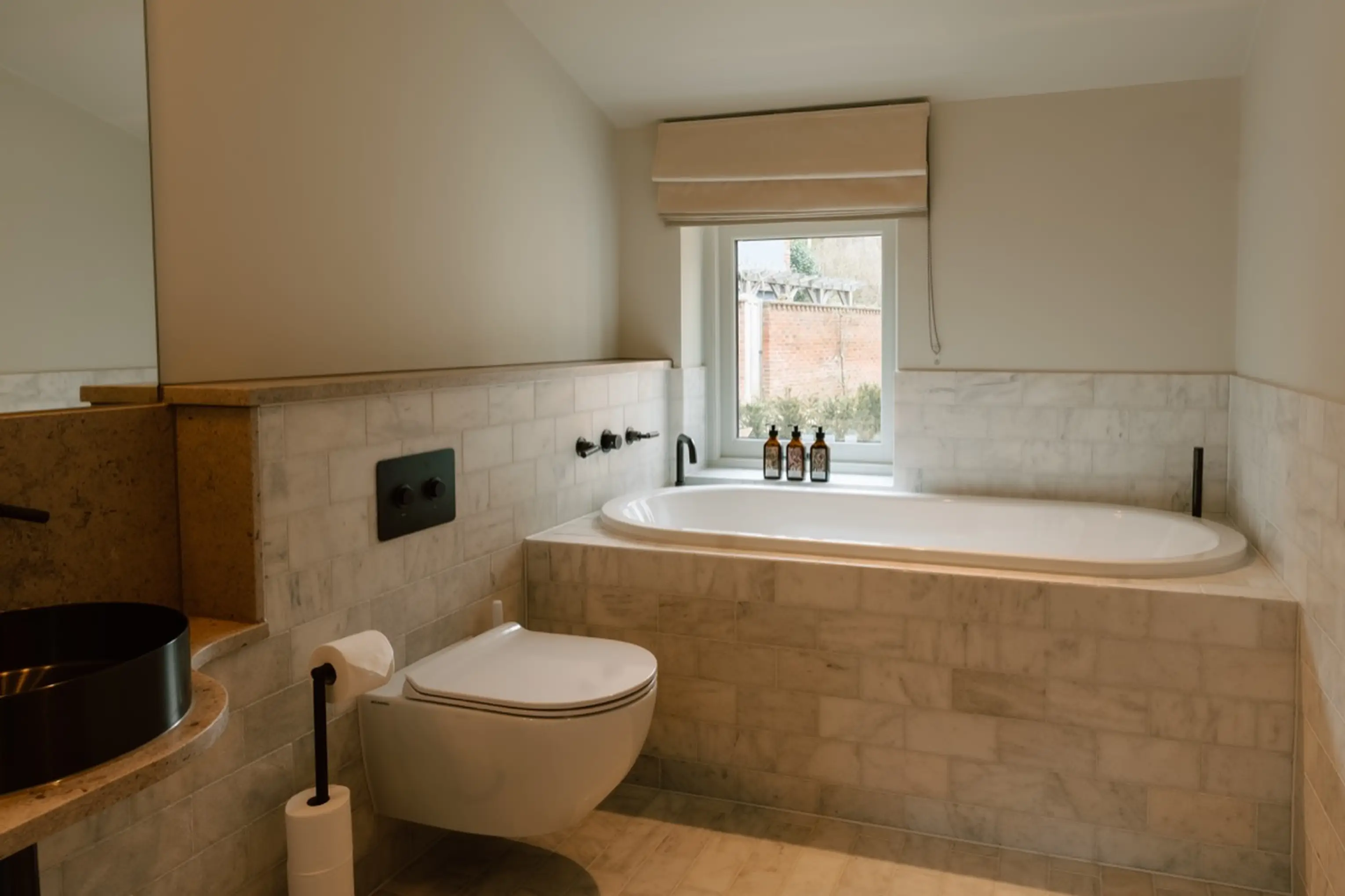 Bathroom at ARC Next-the-Sea with a bath, WC and shelving beneath a window