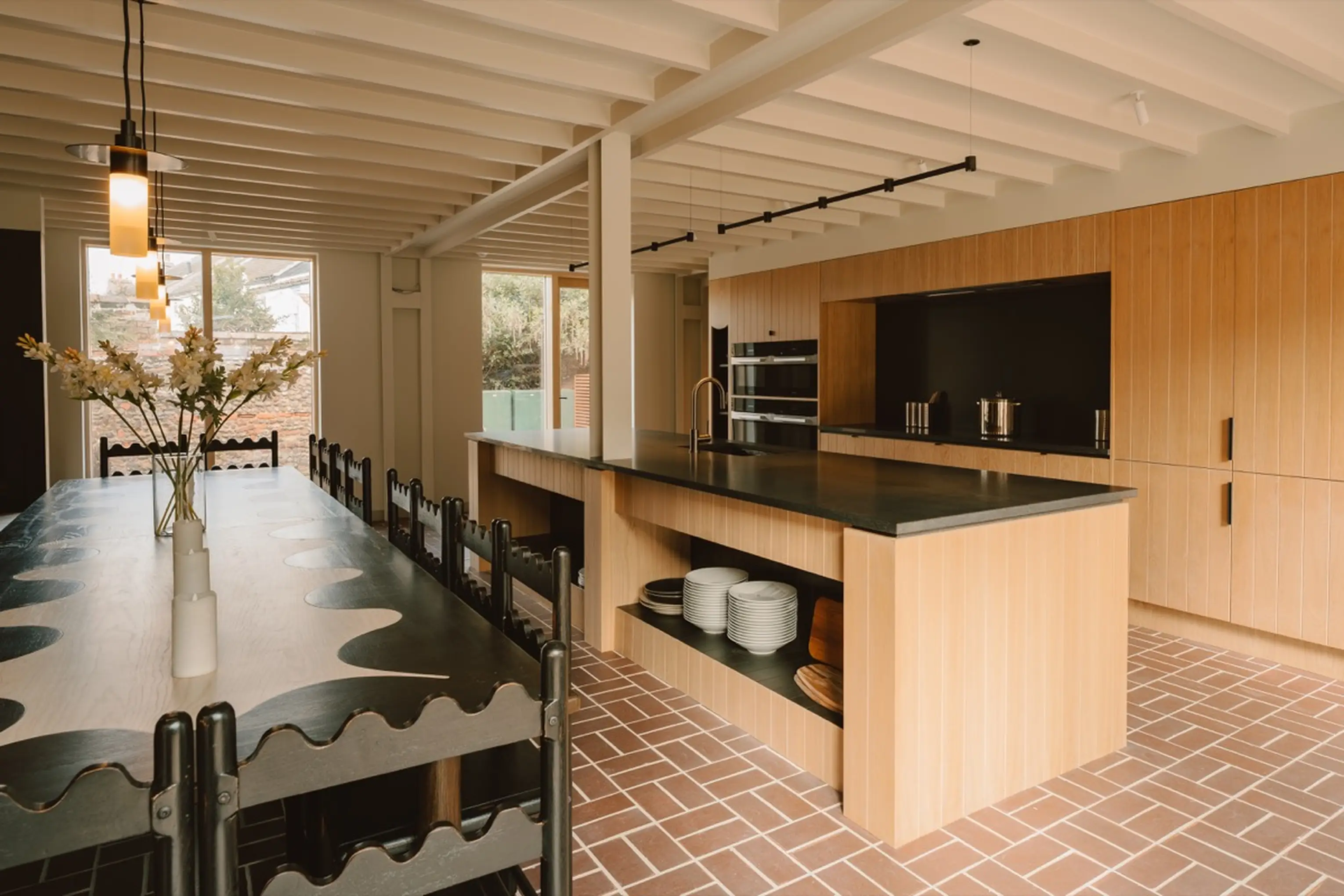 Kitchen at ARC Next-the-Sea with an island, pendant lighting and a dining table beyond