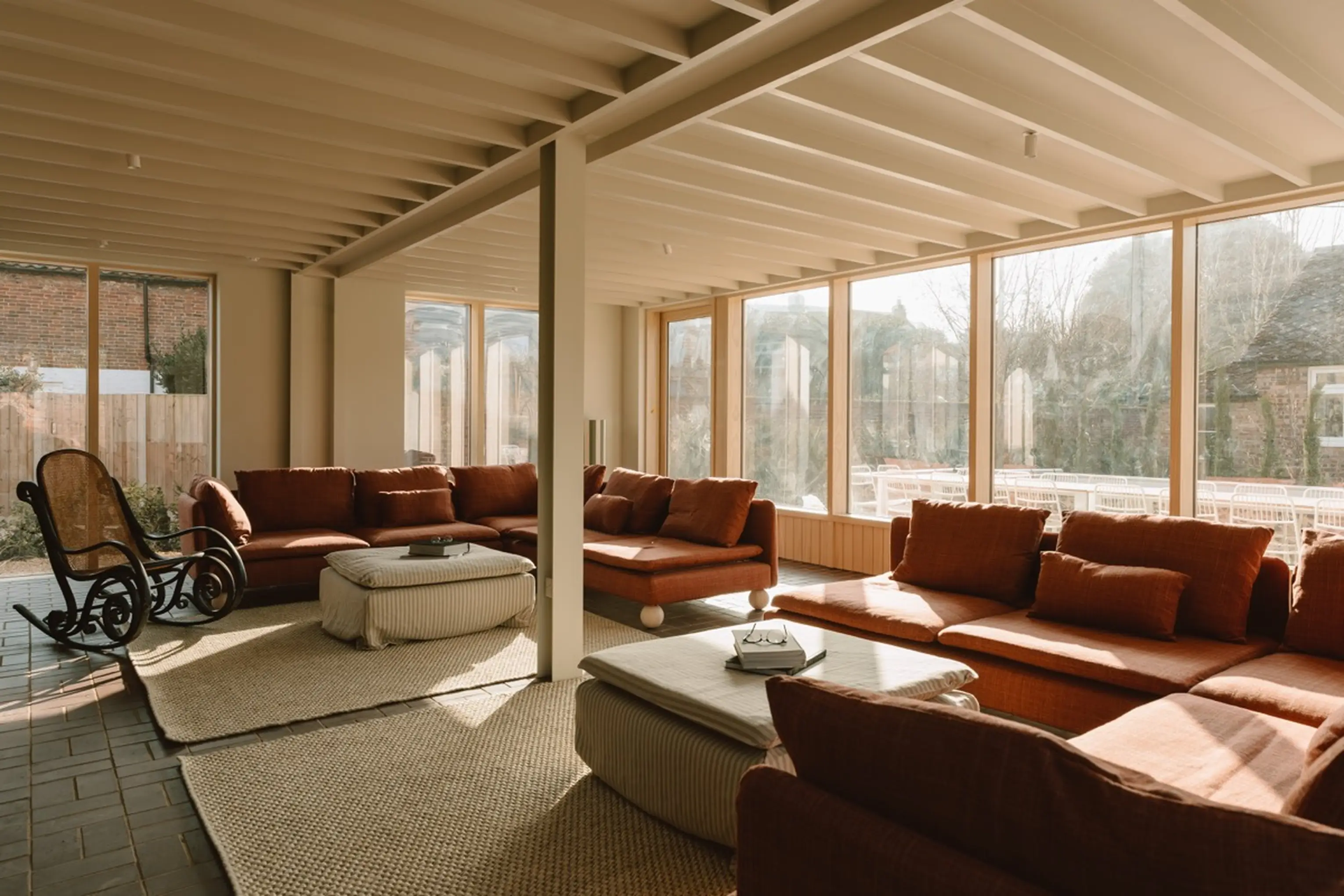 Lounge at ARC Next-the-Sea with large terracotta sofas and a wall of windows onto the garden