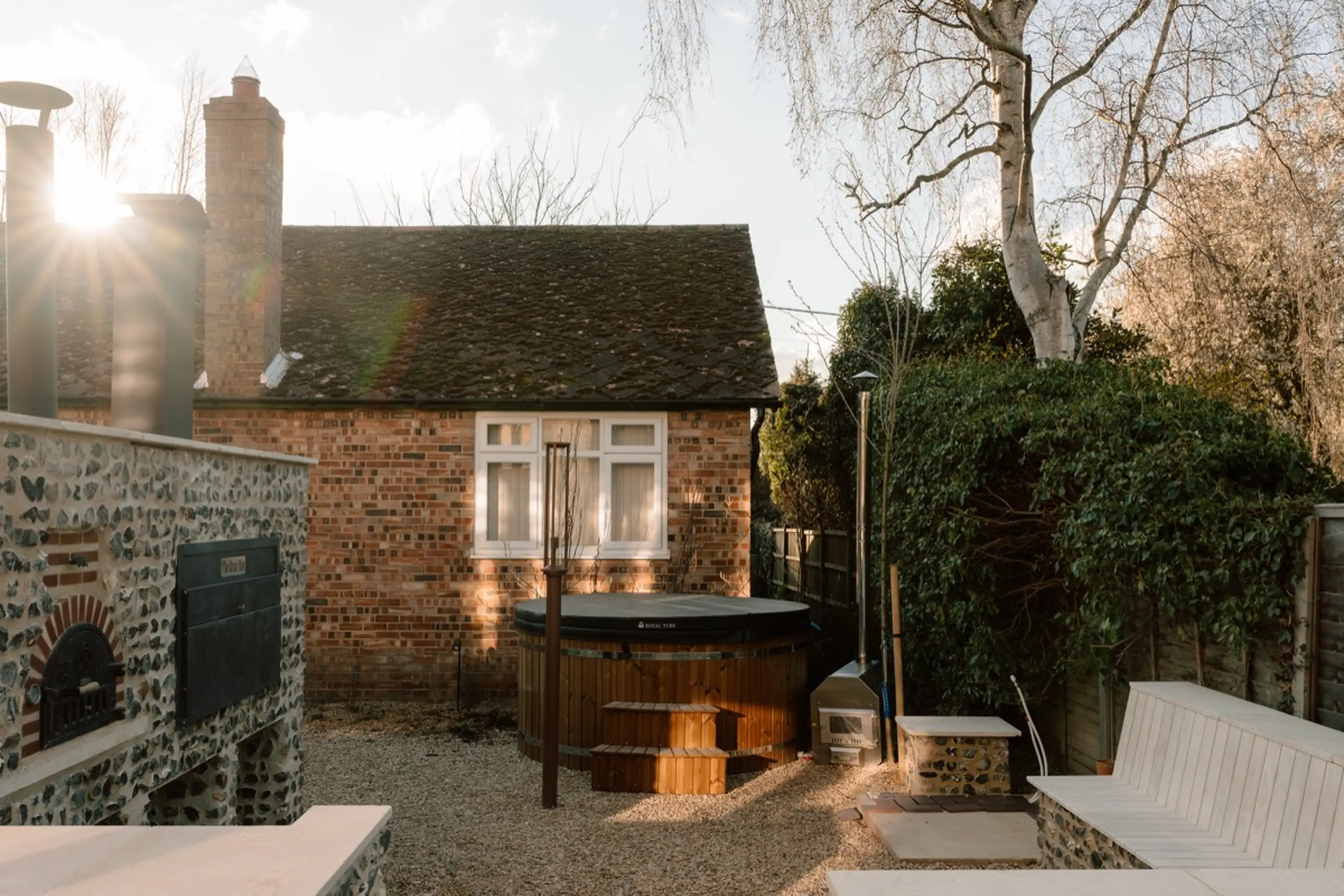 ARC Next-the-Sea at dusk with a wood-fired hot tub, pizza oven and Braii in the garden and low evening sun