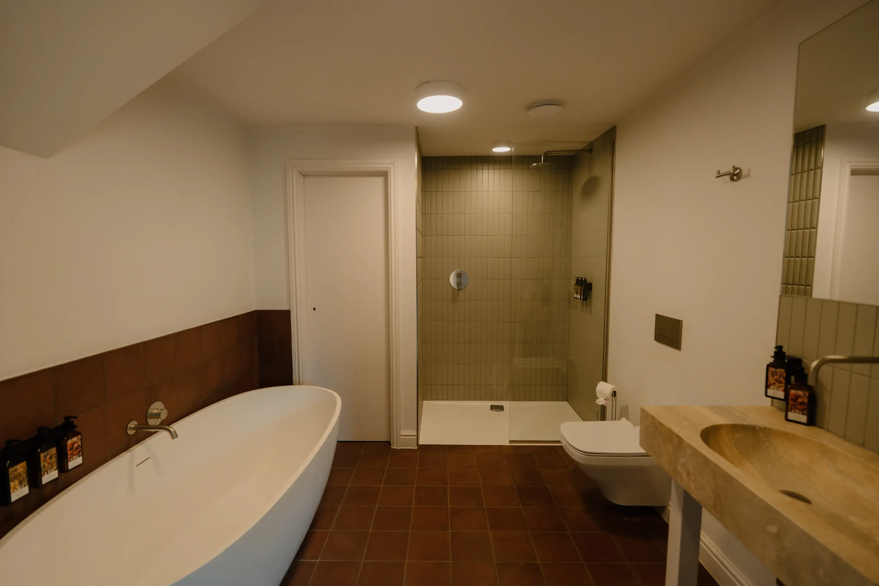 Ensuite at ARC Padstow with a freestanding bath and walk-in shower over a dark tiled floor