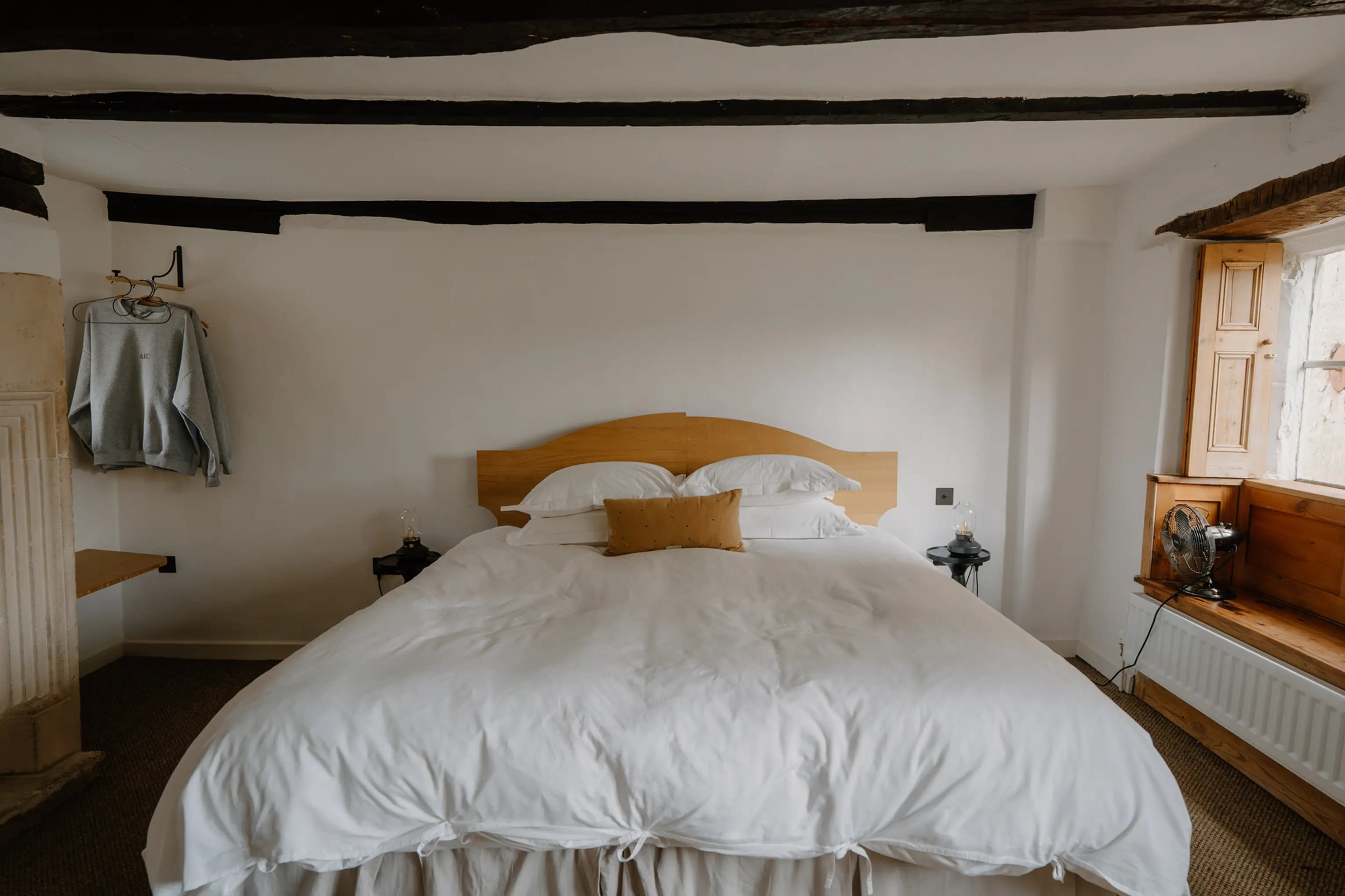 Superking bedroom at ARC Painswick with an arched timber headboard and exposed beams