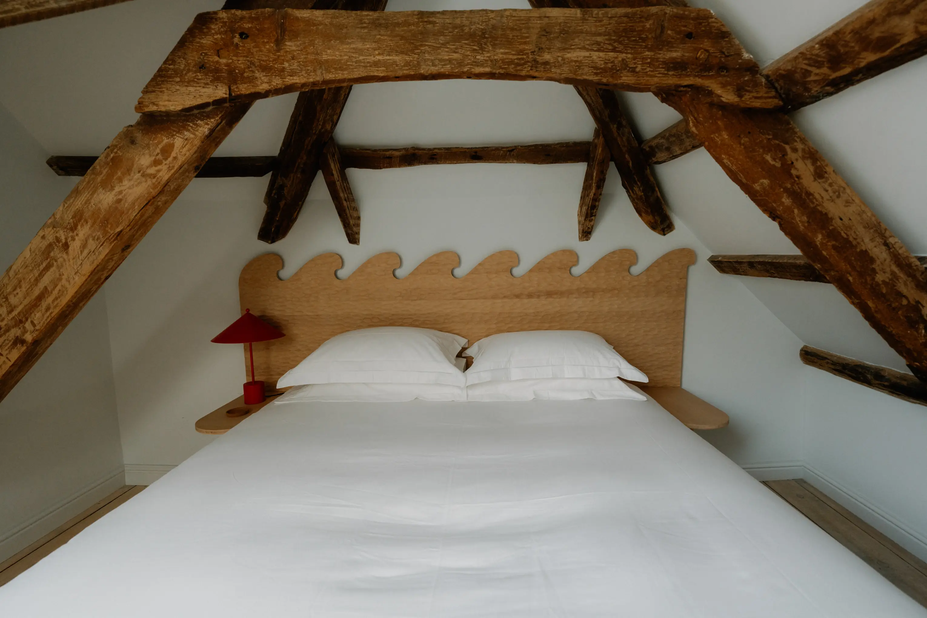 Attic double bedroom at ARC Padstow with a scalloped headboard beneath exposed beams