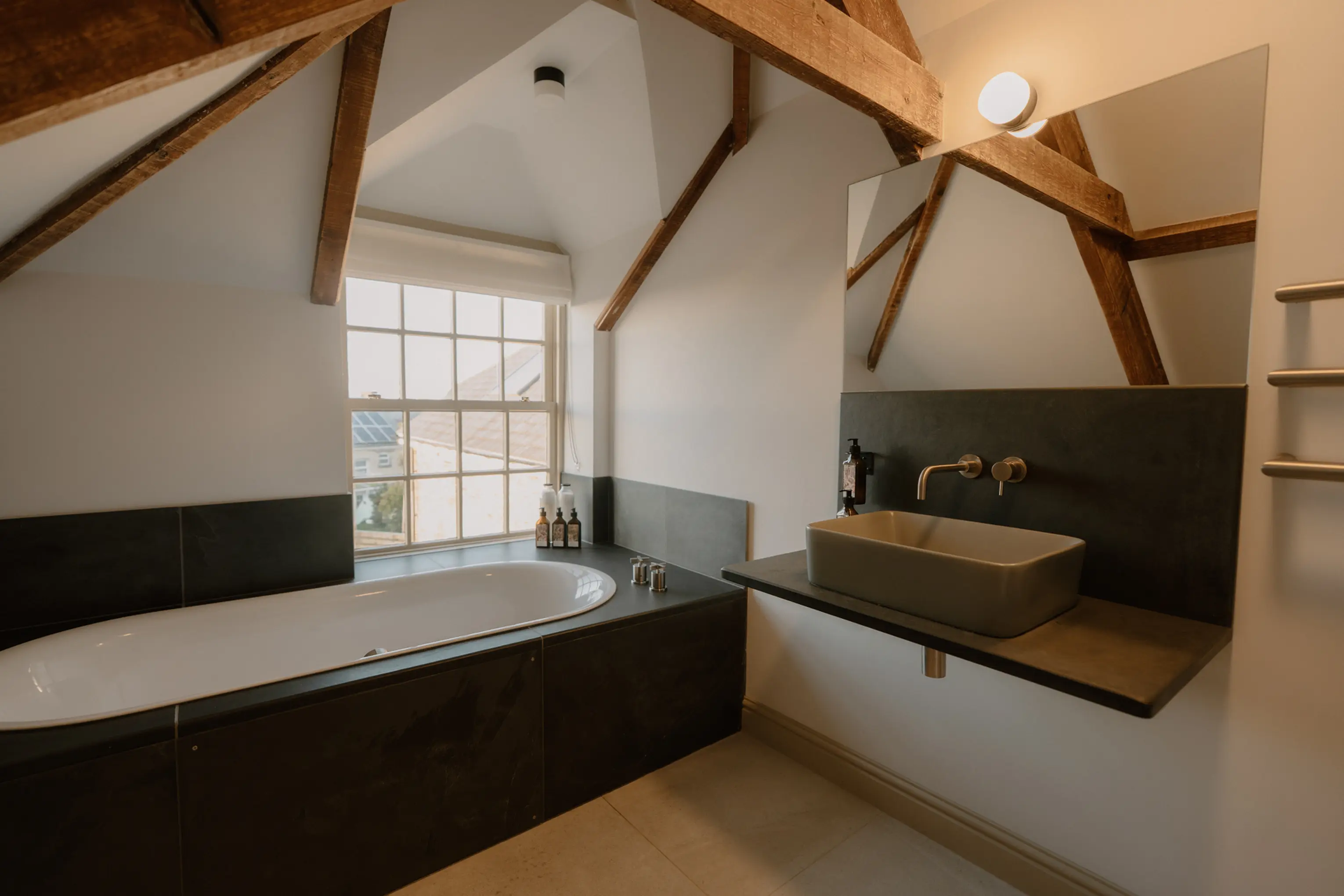 Bathroom under the eaves at ARC Padstow with a freestanding bath beneath an arched window