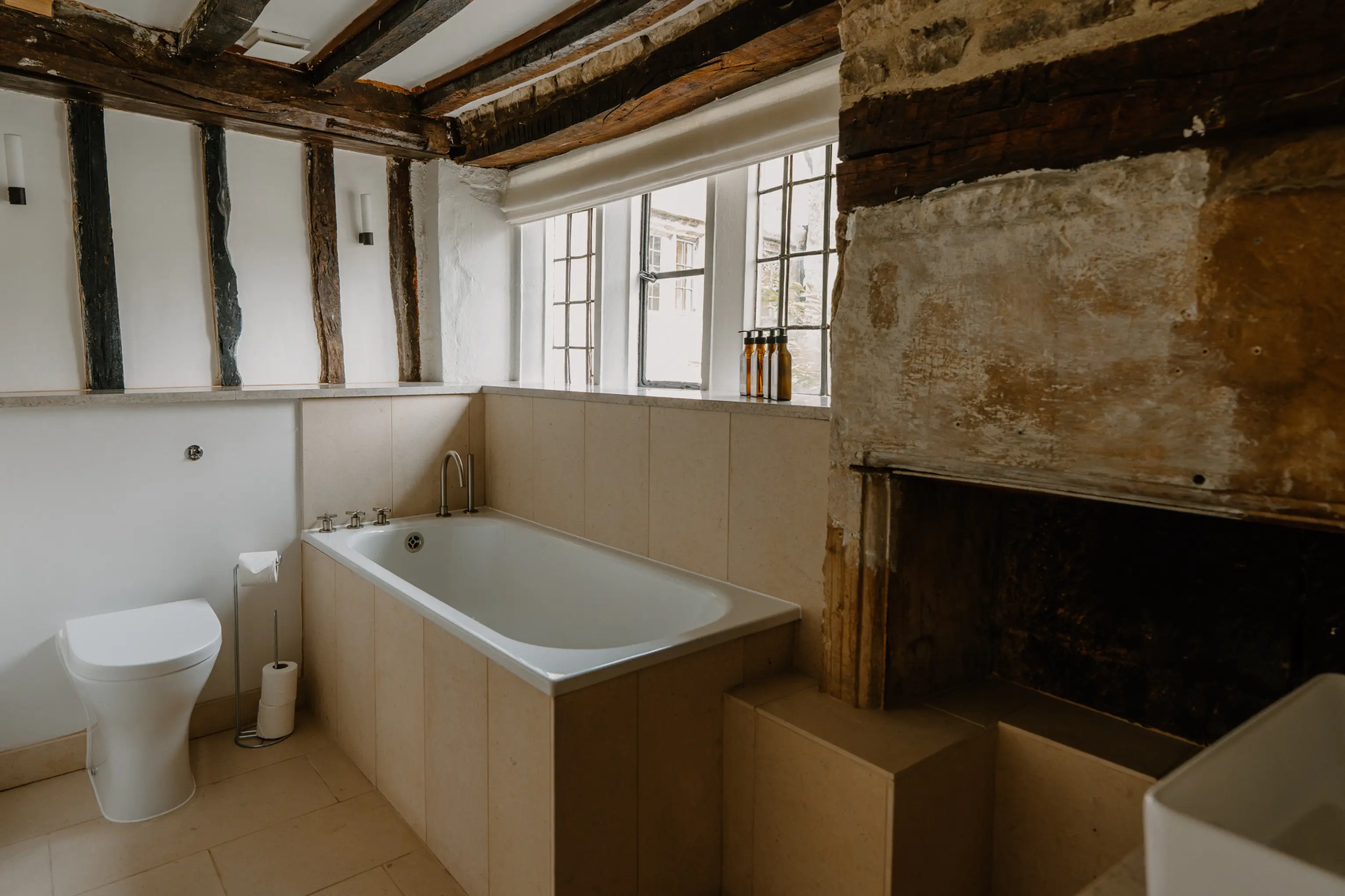 Bathroom at ARC Painswick with a freestanding tub, twin basins and a stone wall