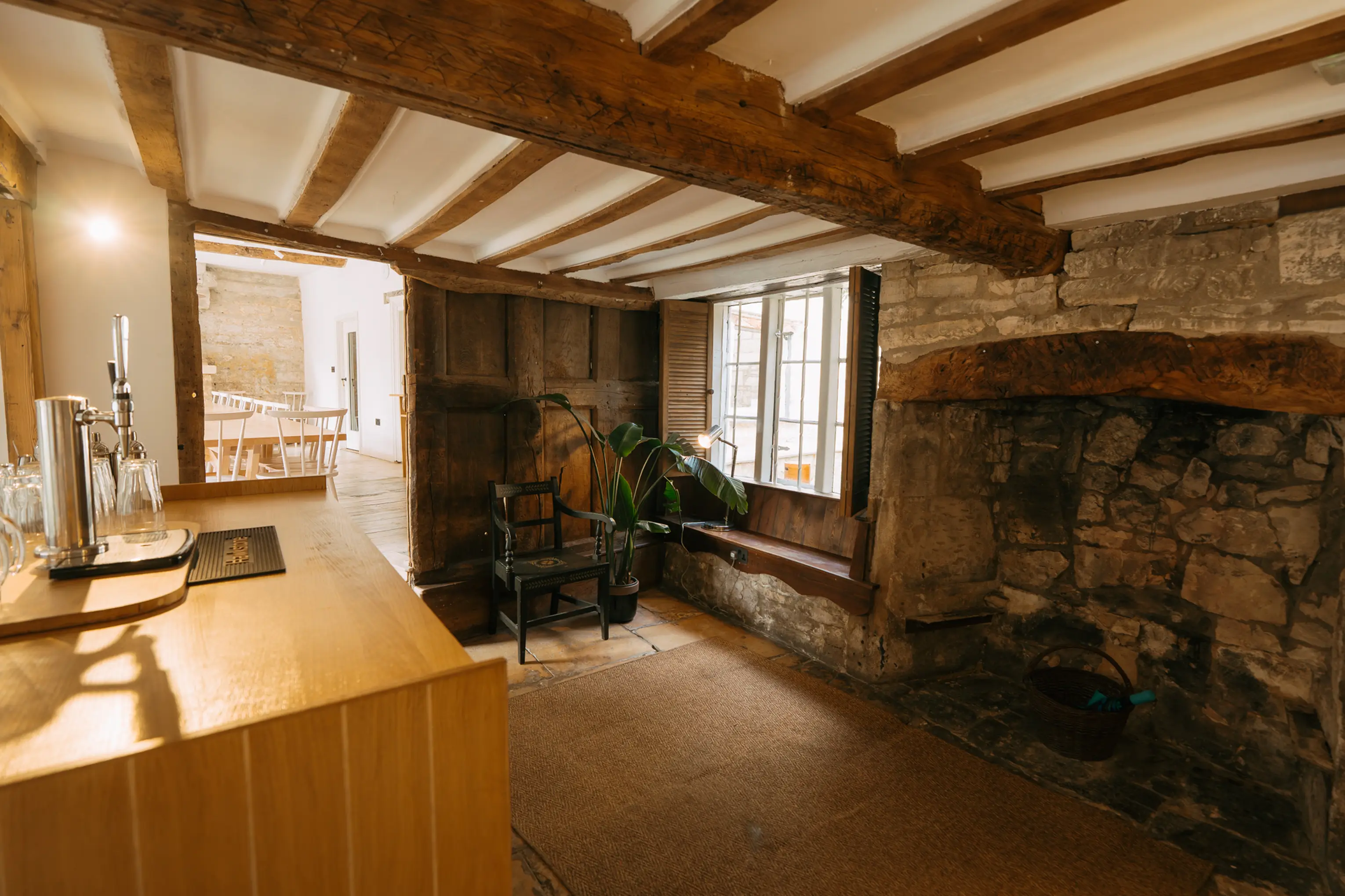 Bar at ARC Painswick with a restored stone fireplace beneath a beamed ceiling