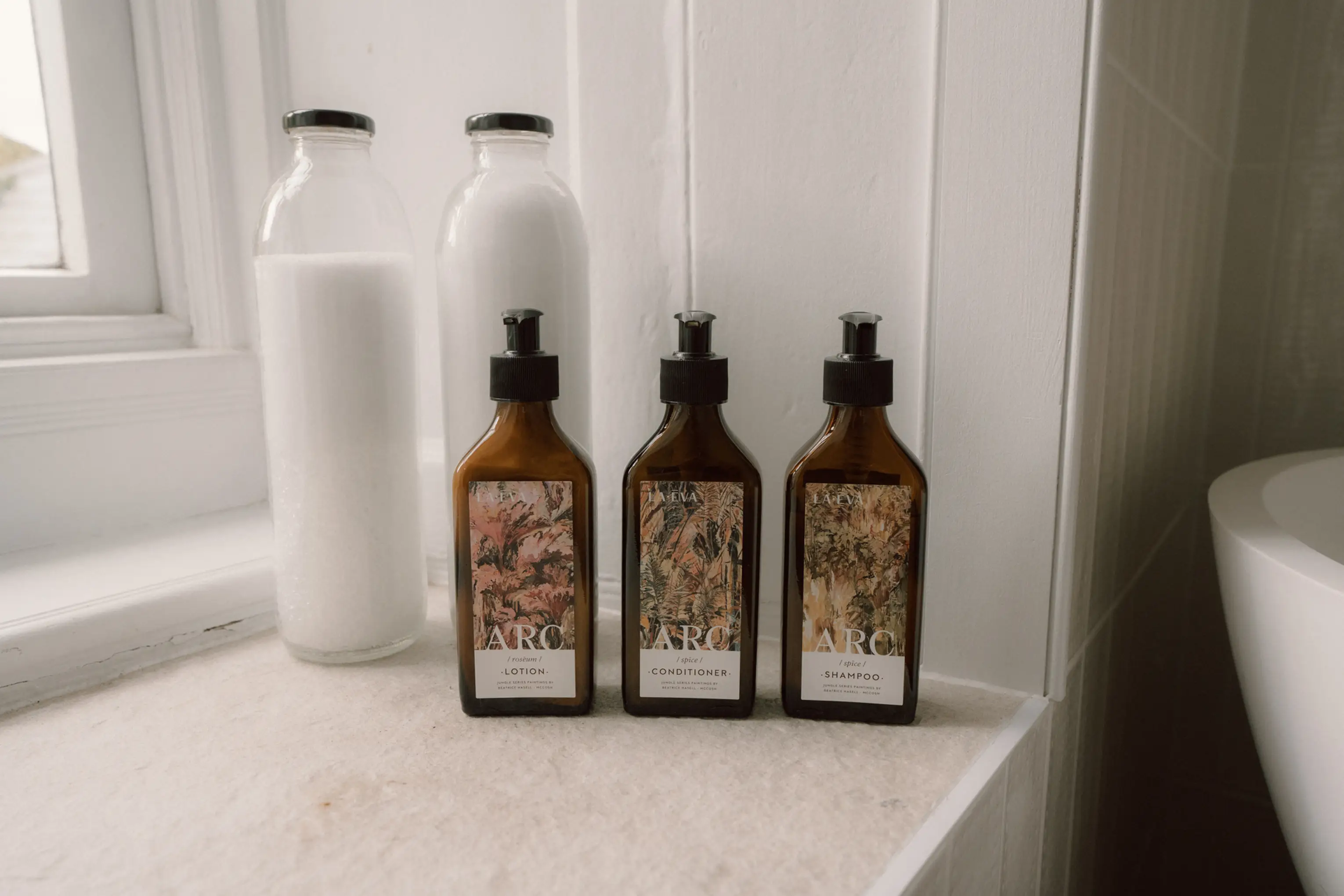 ARC amber toiletry bottles on a shelf beside the bath at ARC Padstow