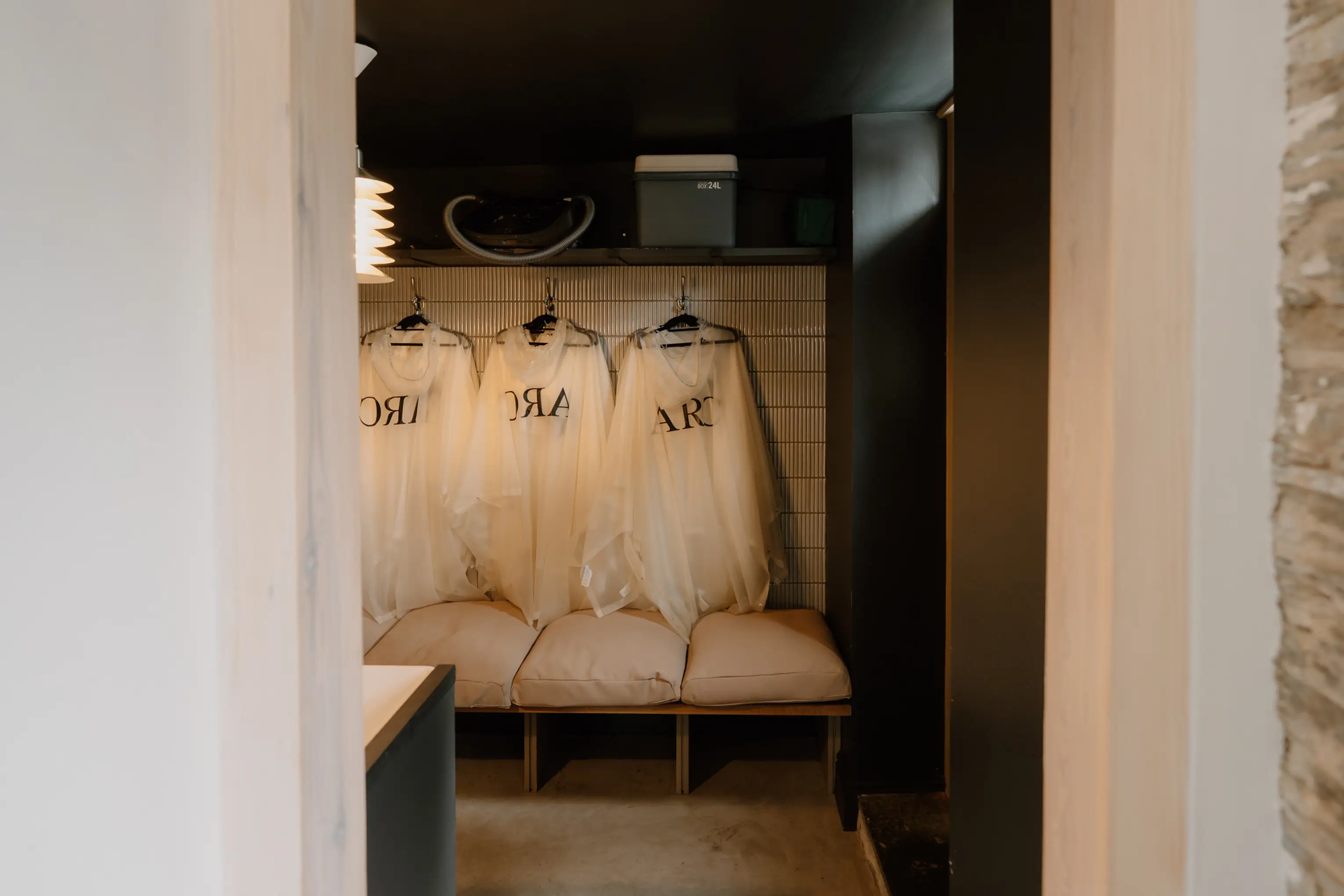 Boot room at ARC Padstow with ARC robes and bags hanging above a bench