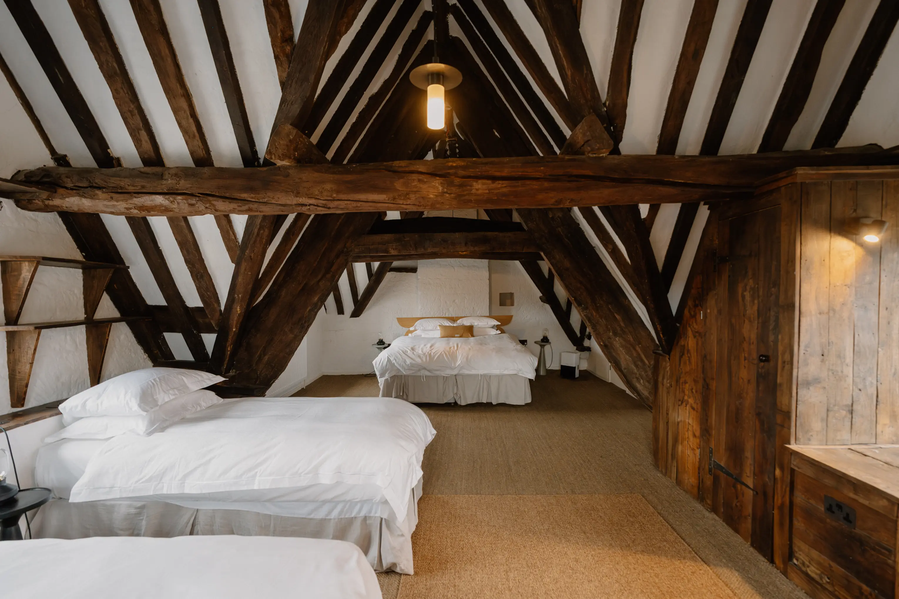 Attic bedroom at ARC Painswick beneath heavy exposed timber beams