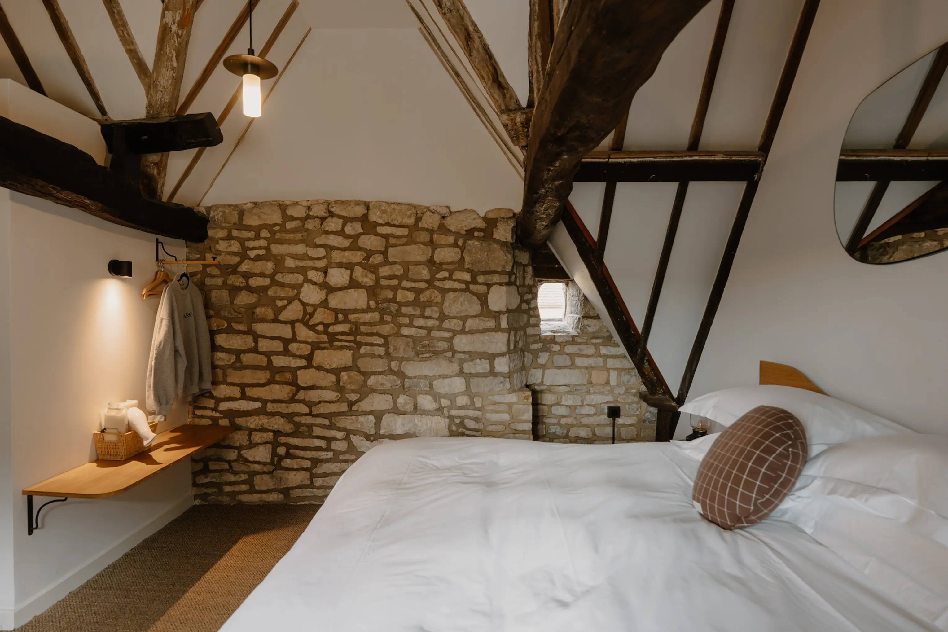 Attic double bedroom at ARC Painswick with a stone wall and exposed beams