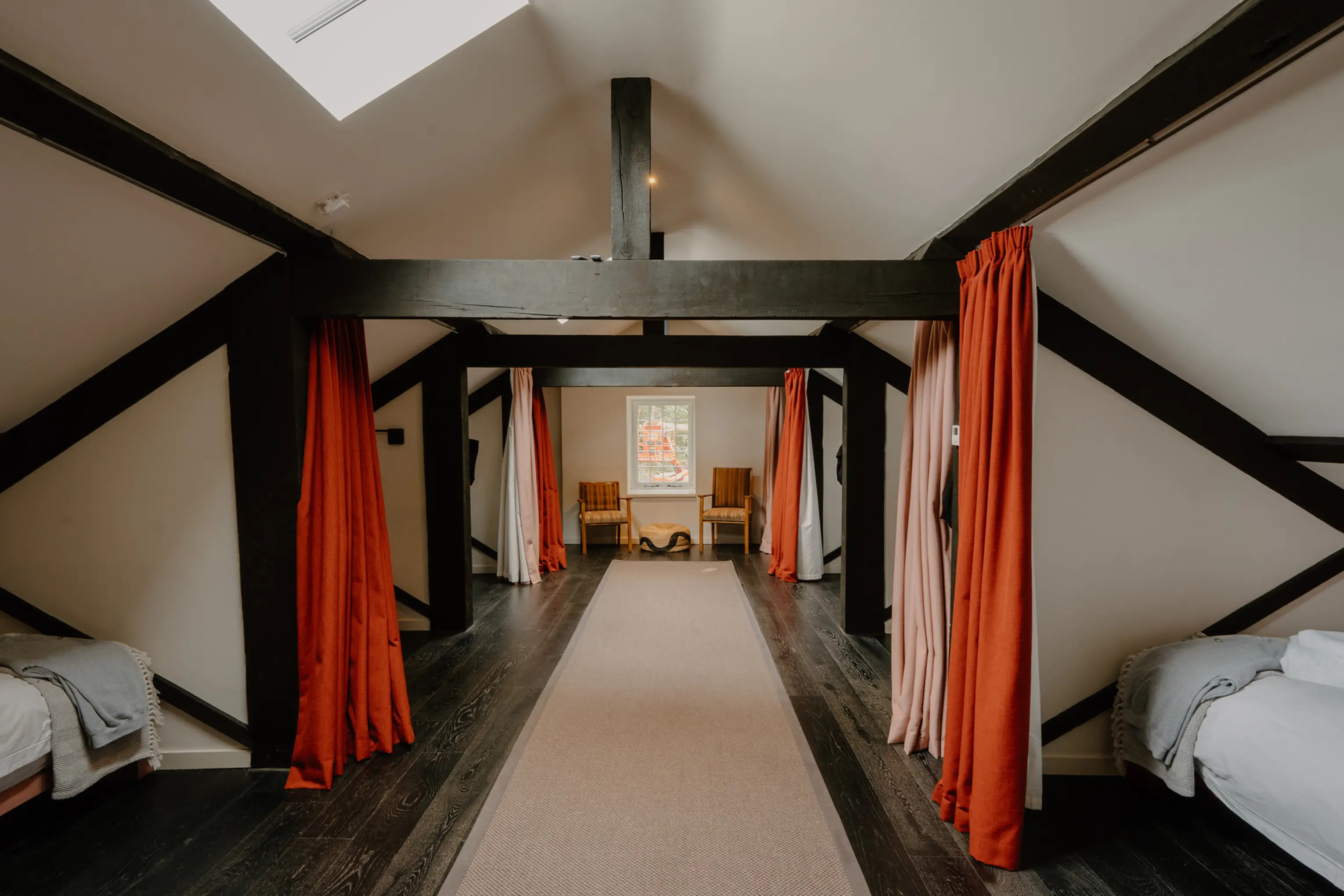 Attic dorm room at ARC Peaks with exposed dark beams and red curtains along a long hallway