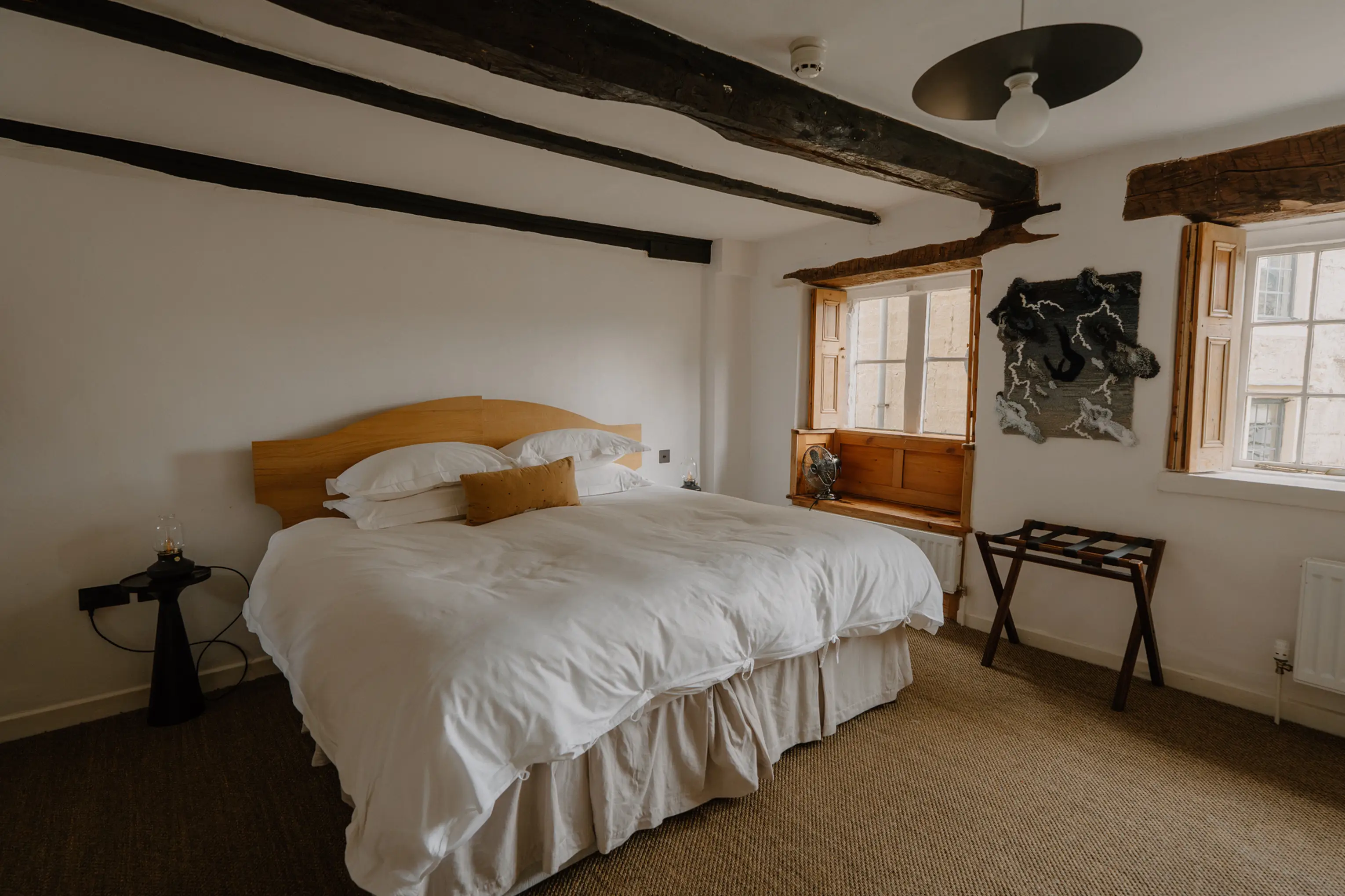 Superking bedroom at ARC Painswick with an arched headboard, bench and artwork