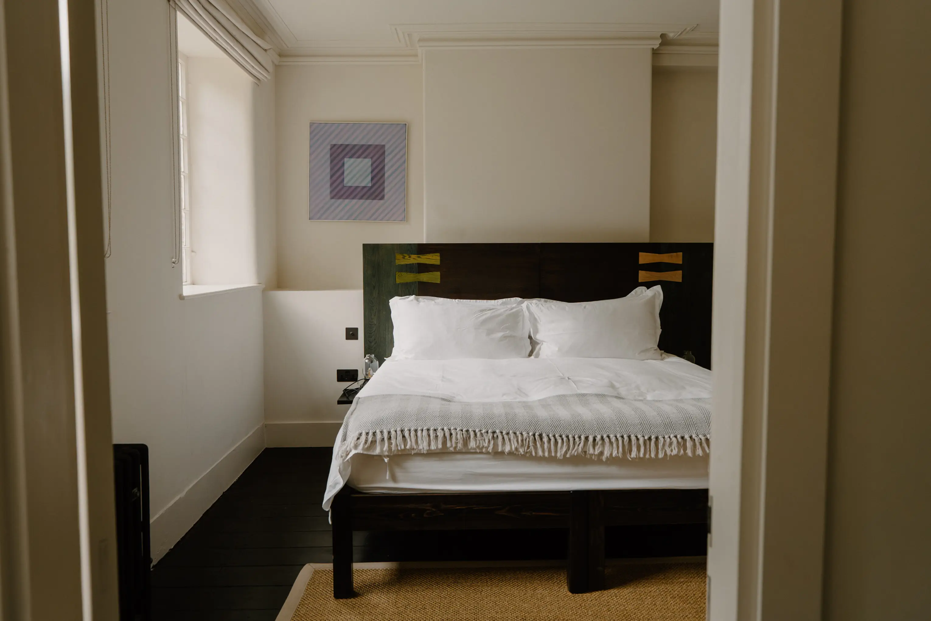 Double bedroom at ARC Peaks with a dark headboard, window and artwork