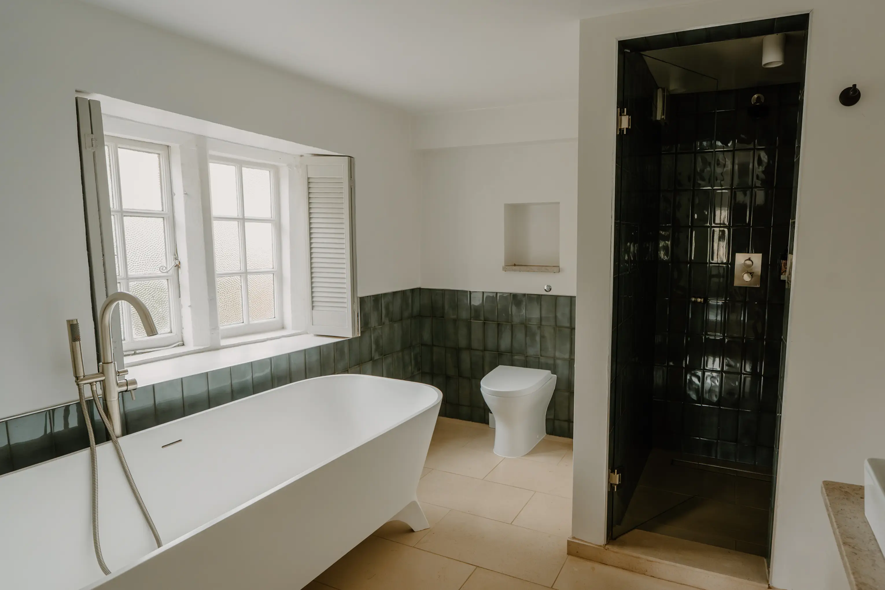 Bathroom at ARC Painswick with a freestanding tub by the window and a walk-in shower