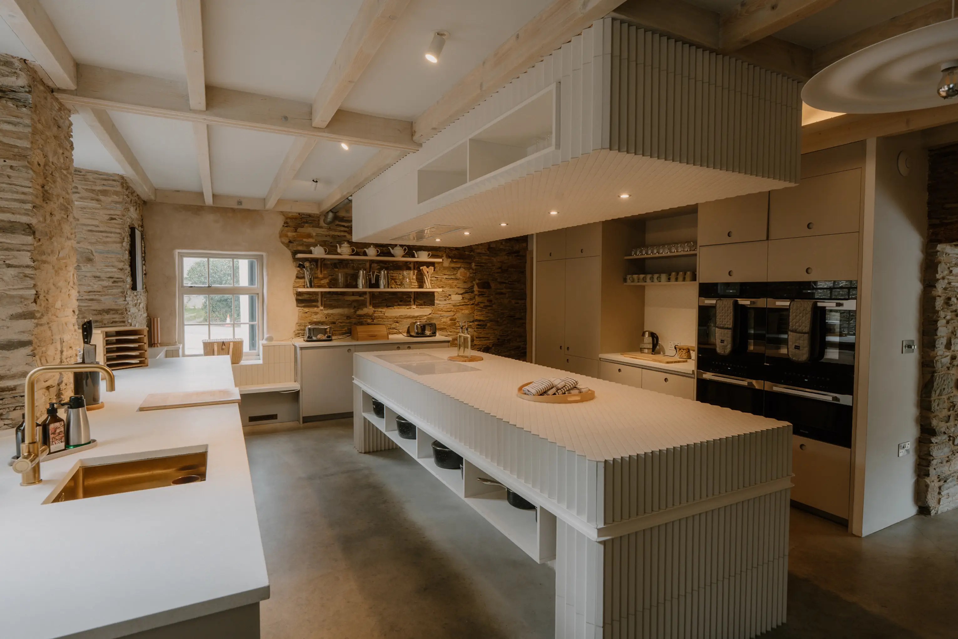 Modern white kitchen at ARC Padstow with a large central island and Miele appliances