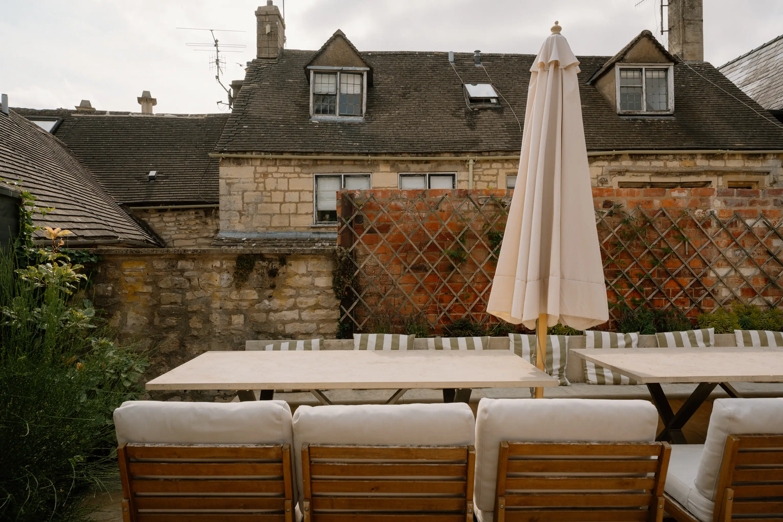 Bespoke stone outdoor dining tables with parasols and cushioned seating in the garden at ARC Painswick