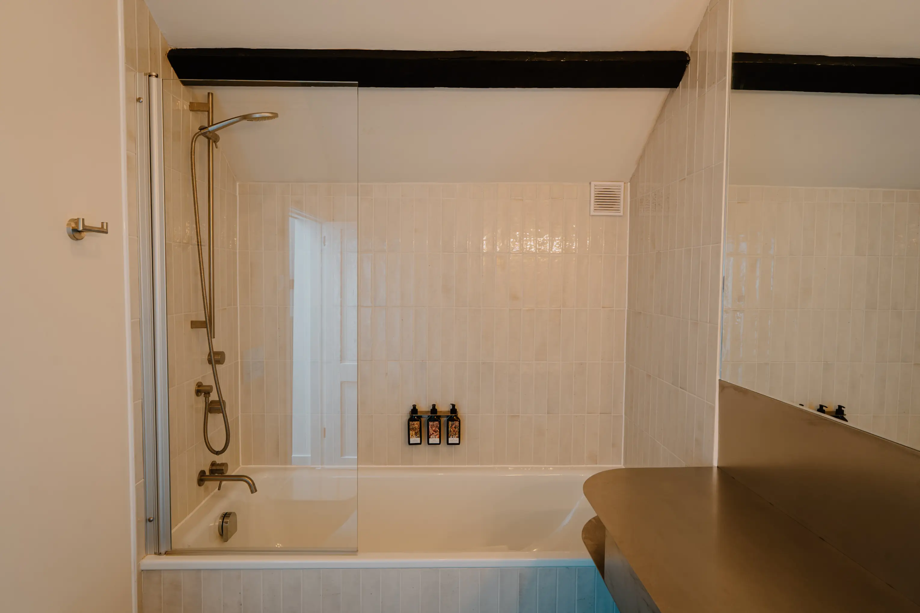 Bathroom under the eaves at ARC Peaks with a walk-in shower, ARC toiletries and exposed beams