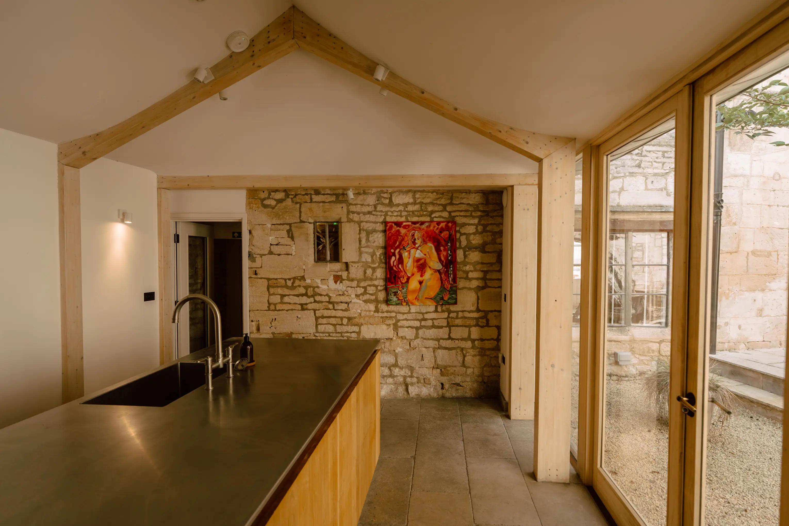 Kitchen at ARC Painswick with a stone island and glass doors onto the courtyard
