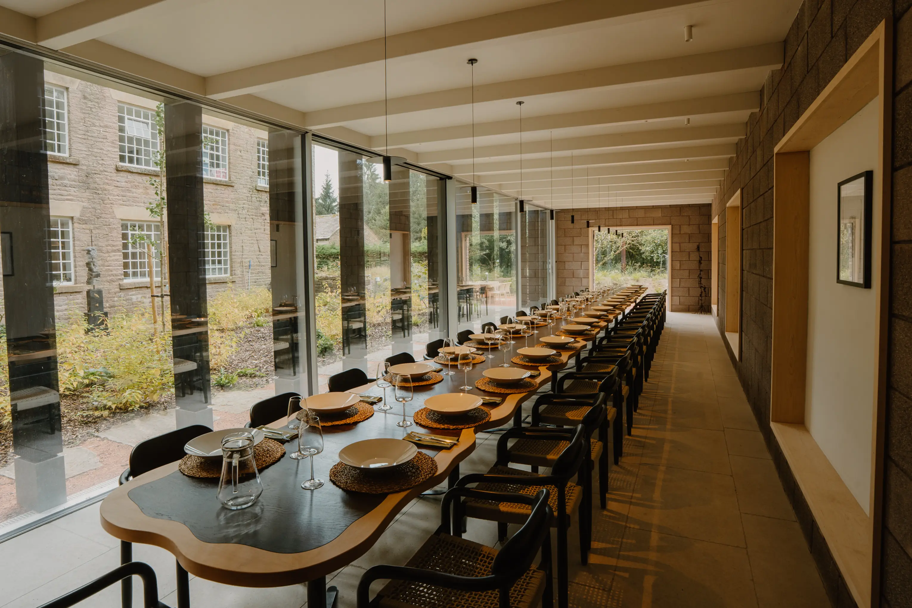 Dining hall at ARC Peaks with a long set table beneath a wall of windows