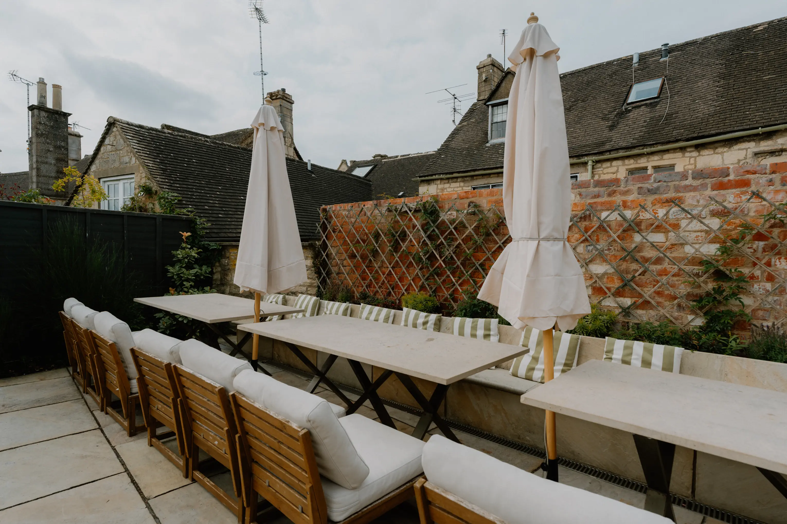 Pool terrace at ARC Painswick with loungers and parasols by a stone wall