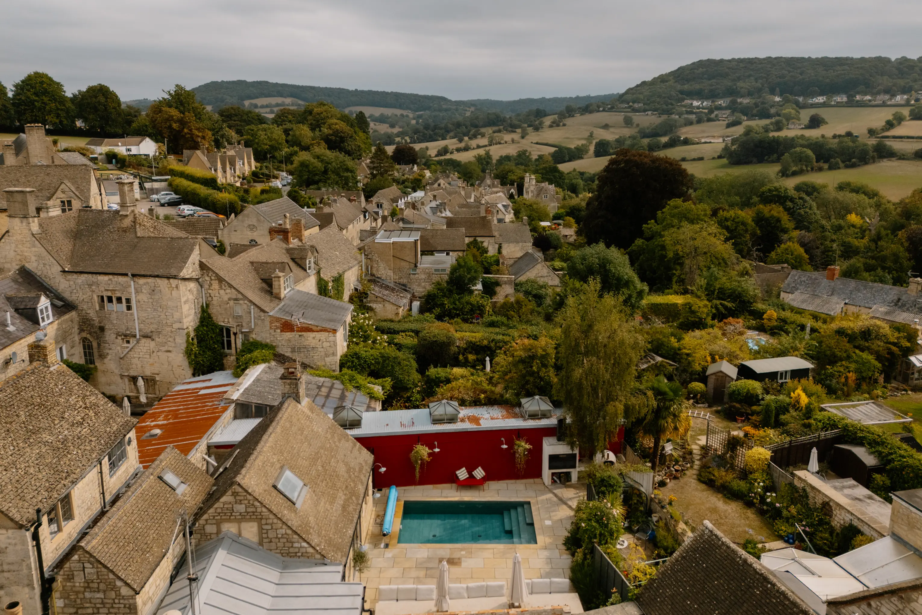 Aerial view over Painswick rooftops and the Cotswold hills, with the ARC pool below