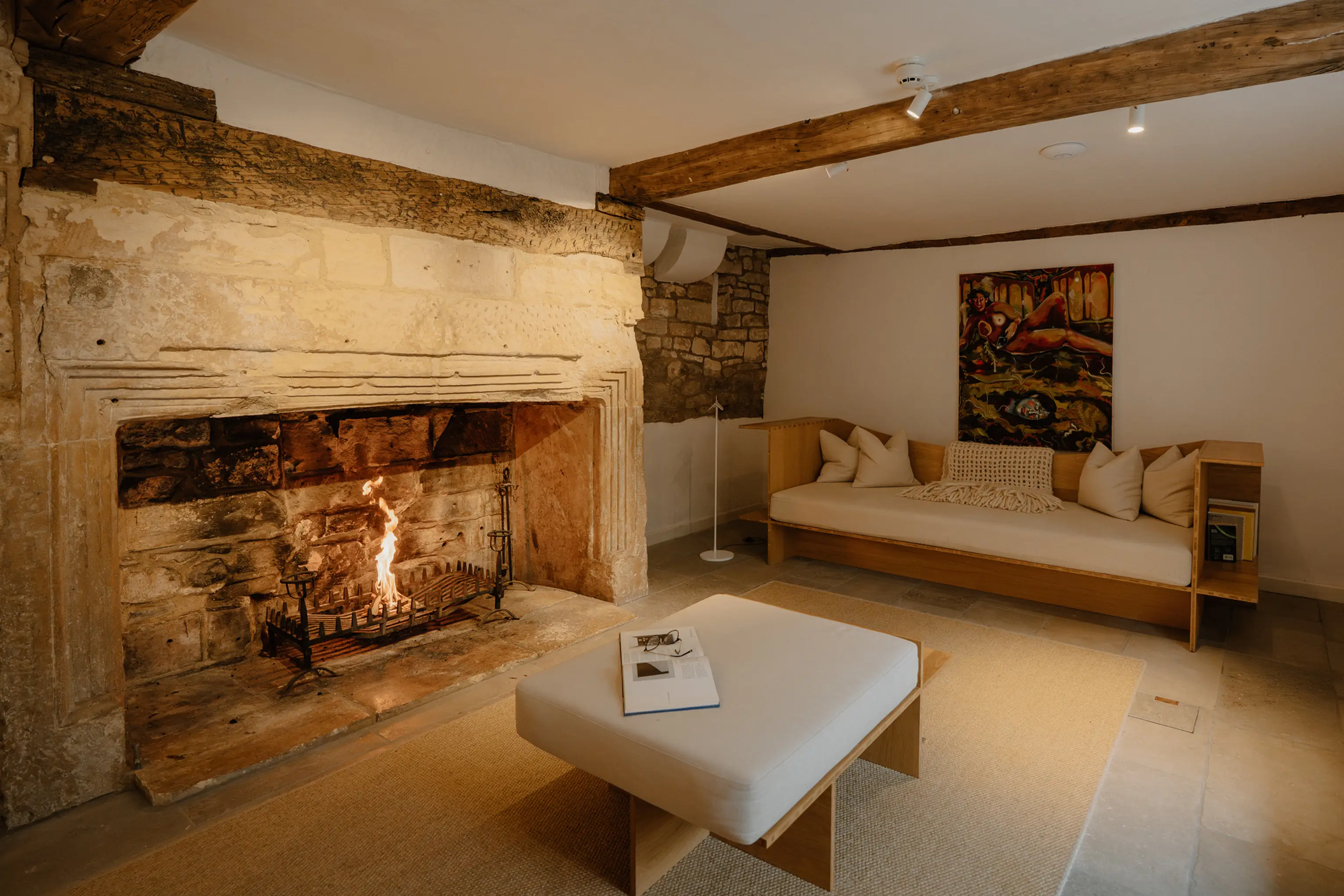 Large stone inglenook fireplace with a lit fire at ARC Painswick