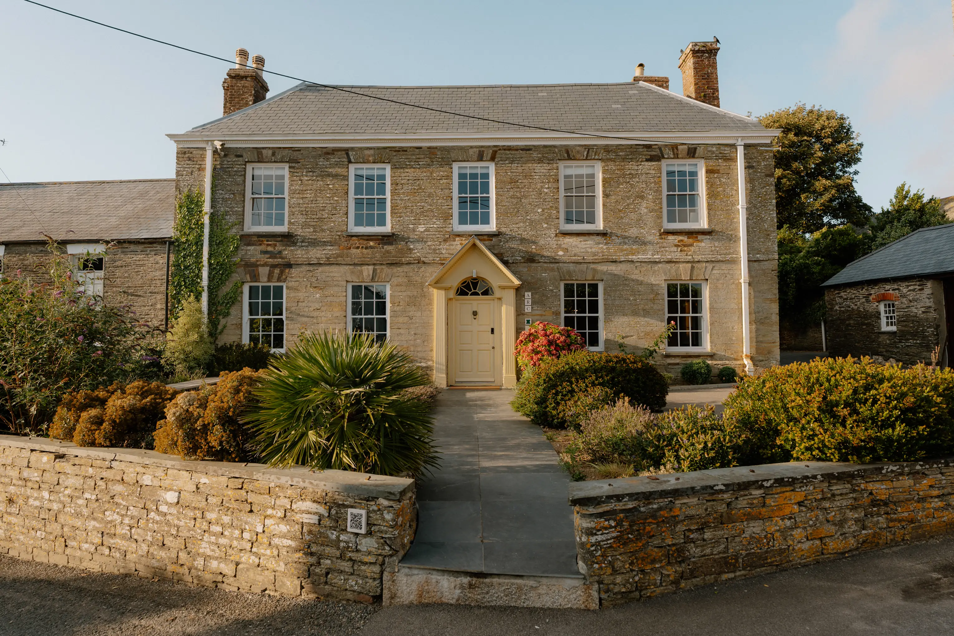 The Georgian stone facade of ARC Padstow with its central door and gravel forecourt in St Issey, Cornwall
